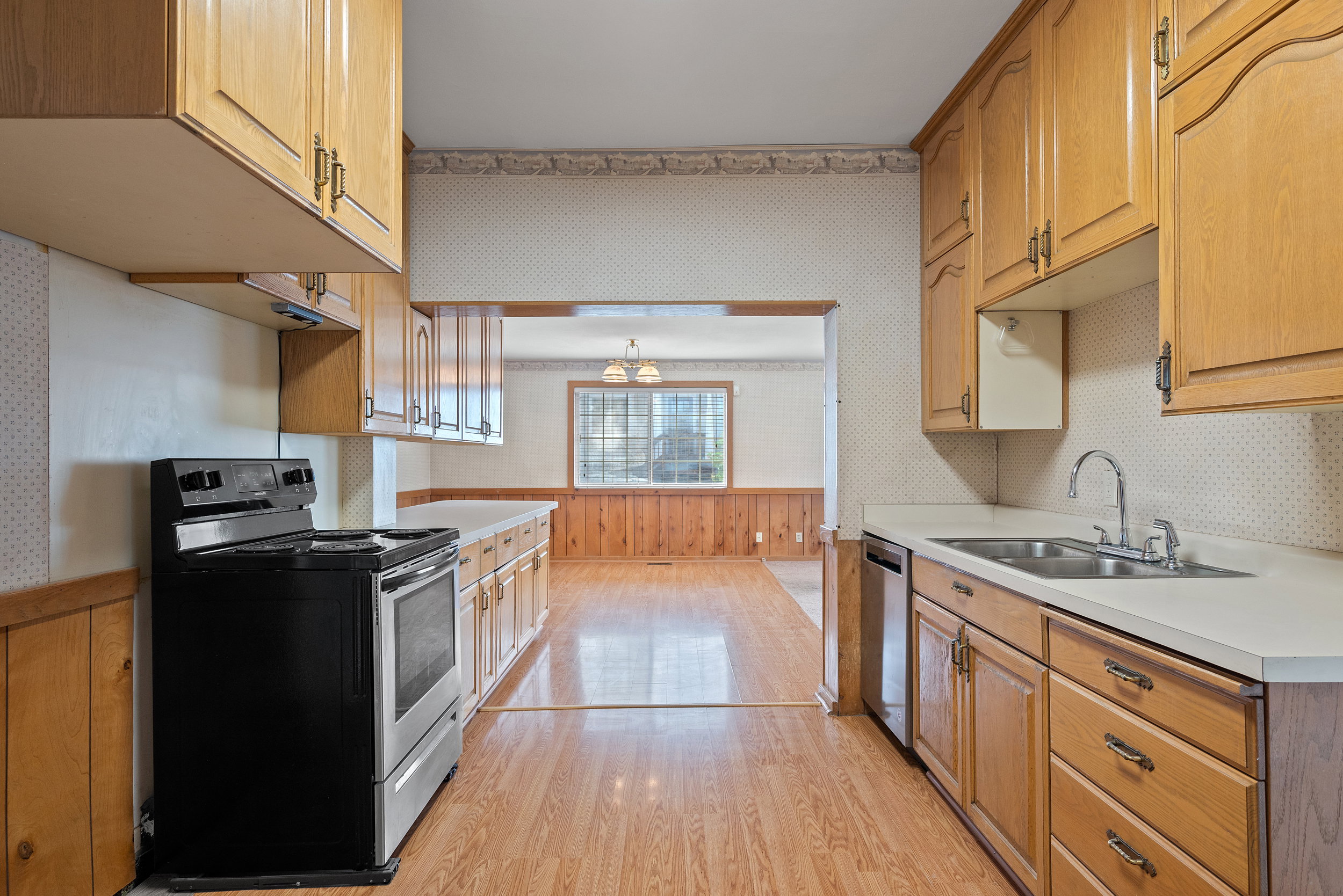 Galley kitchen featuring wood-finish flooring, wood cabinetry, and laminate countertops
