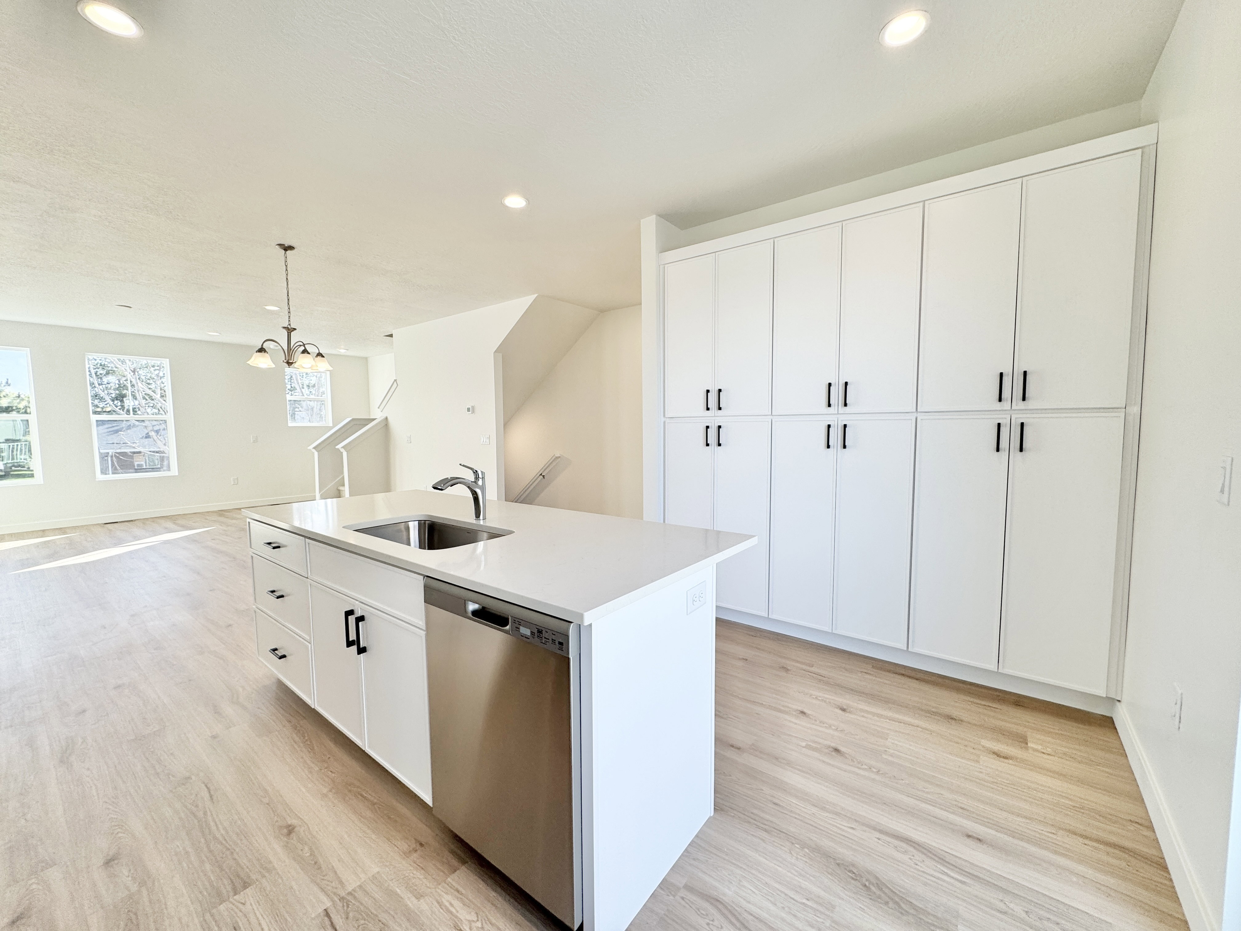 Kitchen island with integrated sink and dishwasher, featuring a white countertop and white cabinetry with black hardware