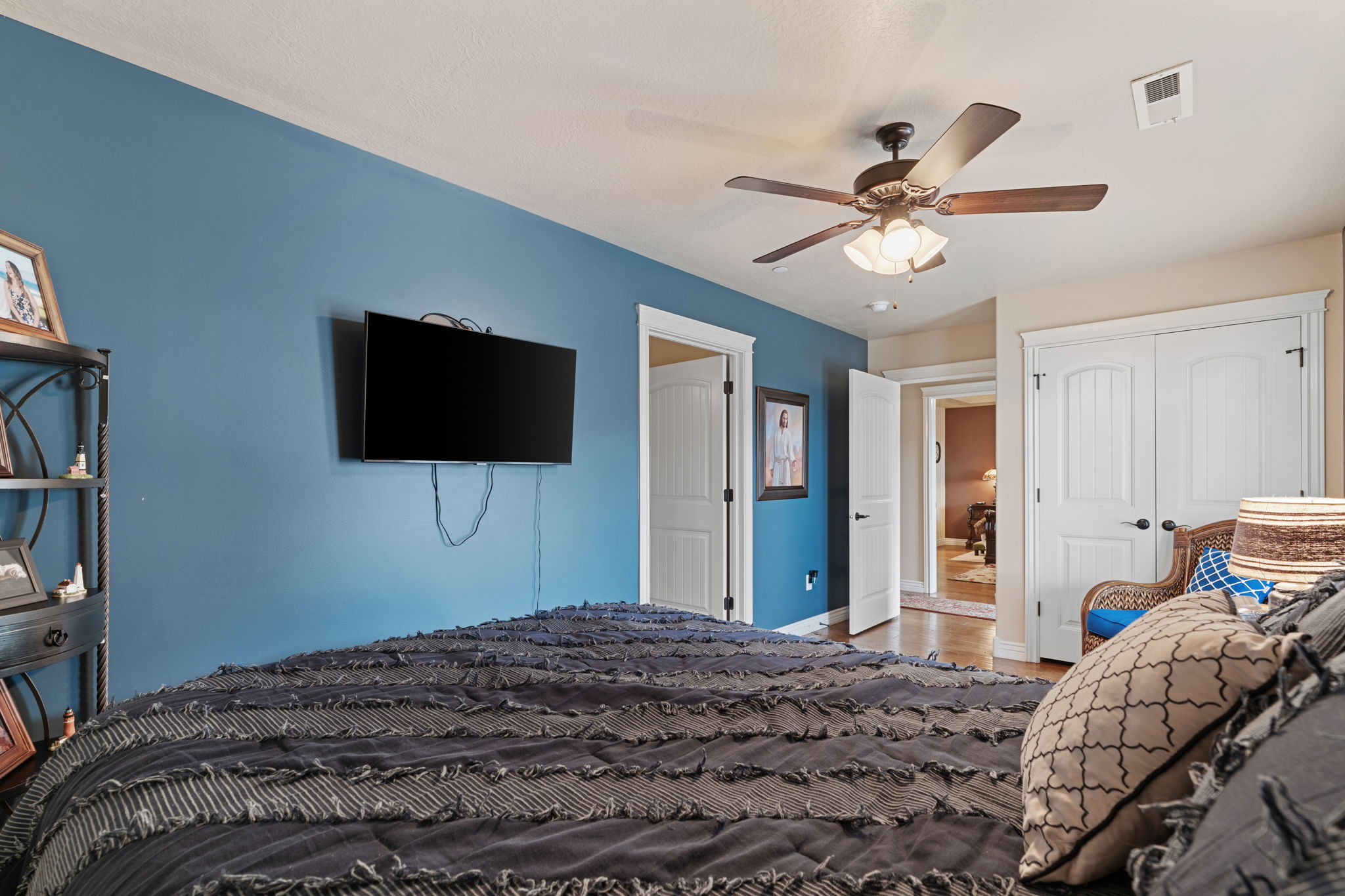 Bedroom featuring a ceiling fan with integrated lighting, wood-finish flooring, and white paneled doors