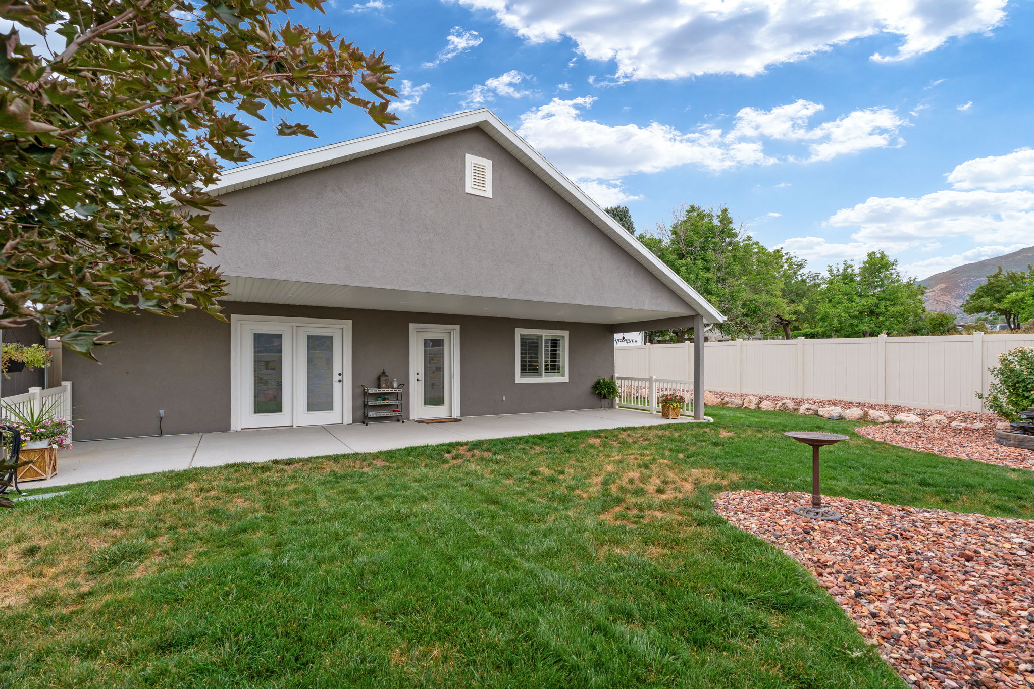 Expansive backyard featuring a covered patio, dual French doors, a single exterior door, and a privacy fence