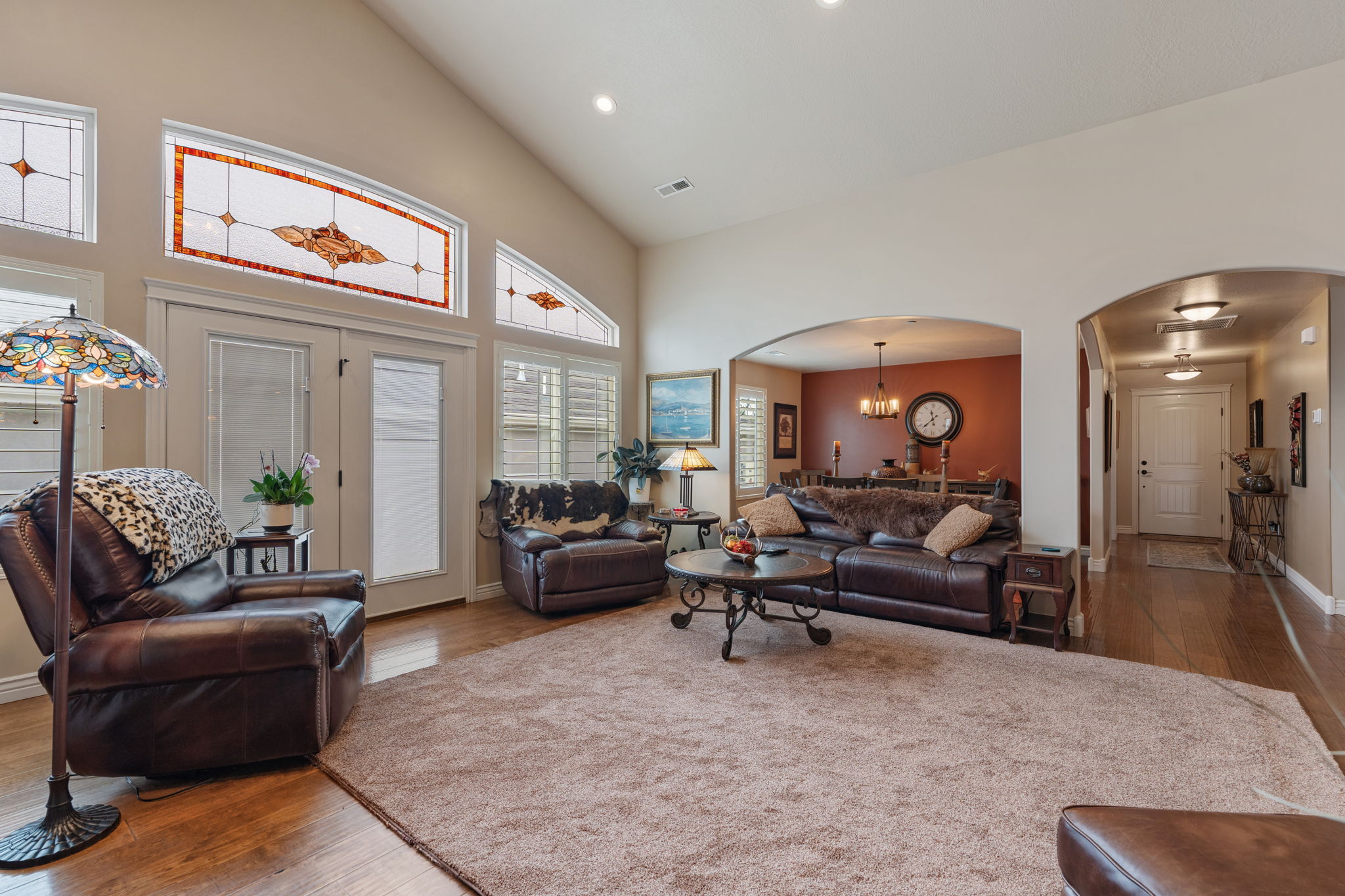 Vaulted ceilings in the living area featuring wood-finish flooring, recessed lighting, and stained glass transom windows