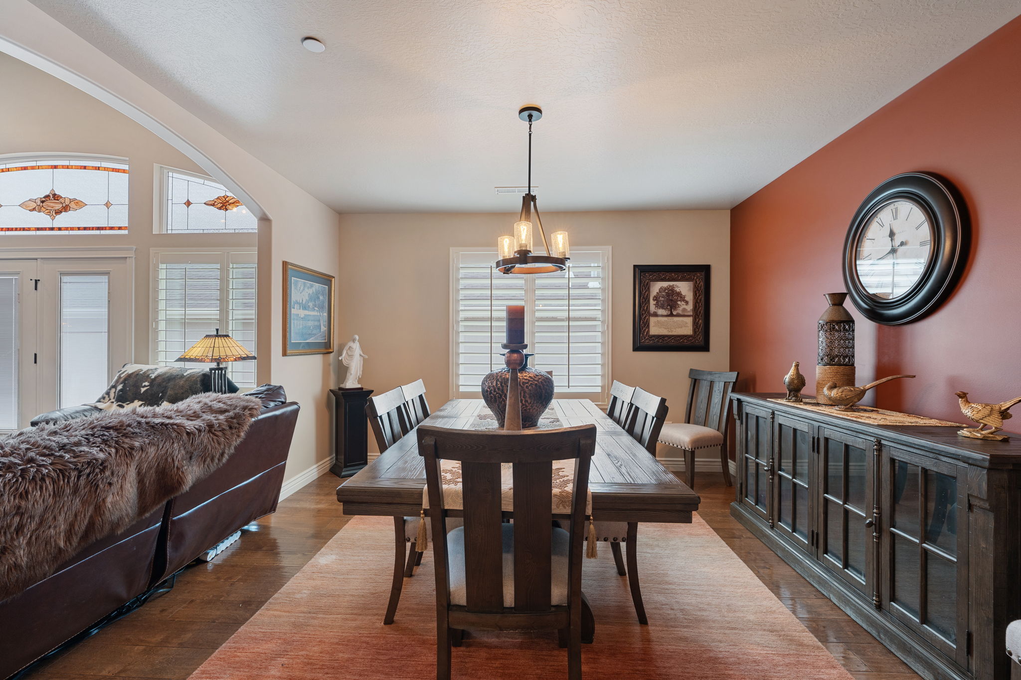 Dining space featuring wood-finish flooring, a contemporary chandelier, and a decorative accent wall