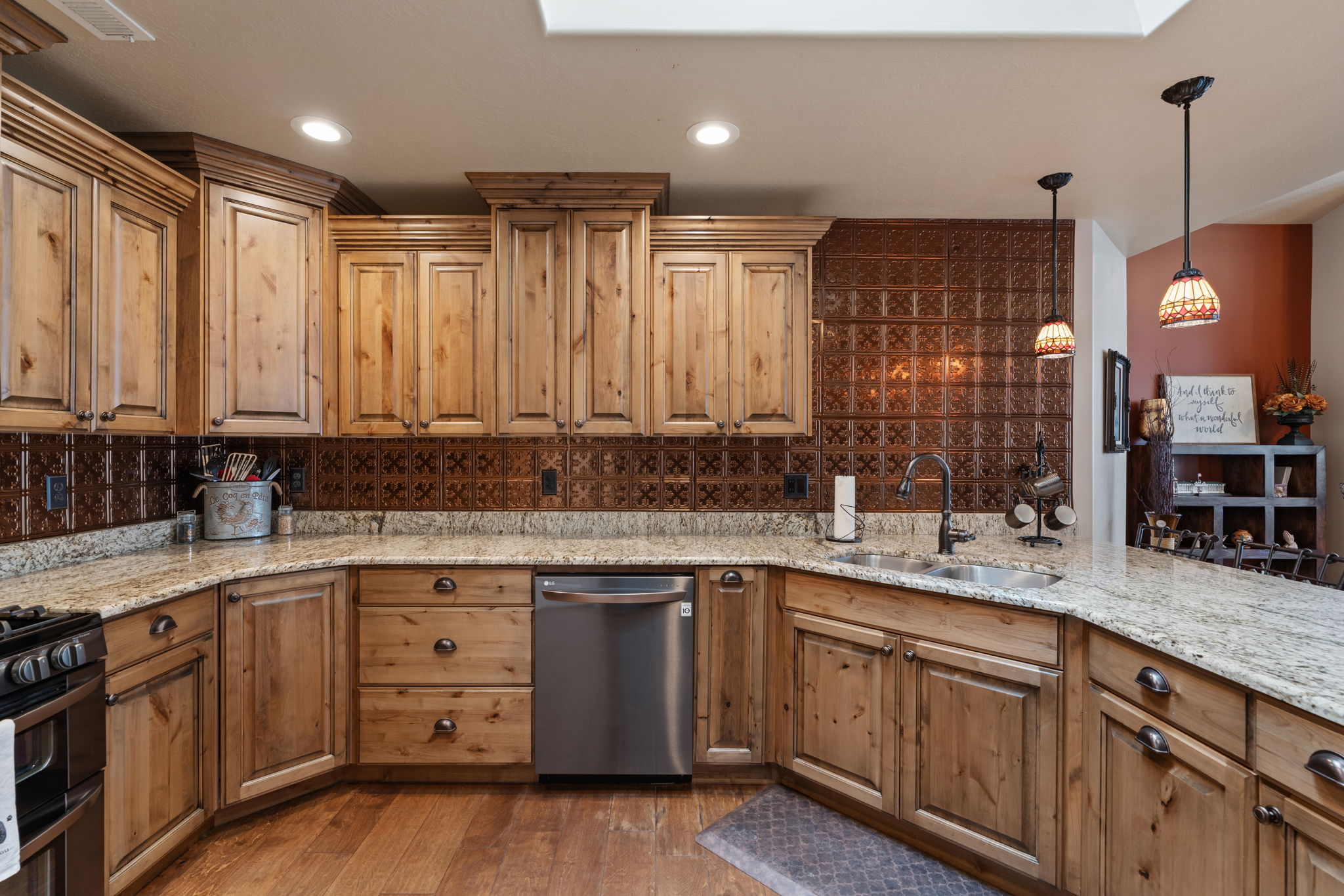 Kitchen featuring knotty wood cabinetry, stone countertops, stainless steel appliances, a tin tile backsplash, and recessed lighting