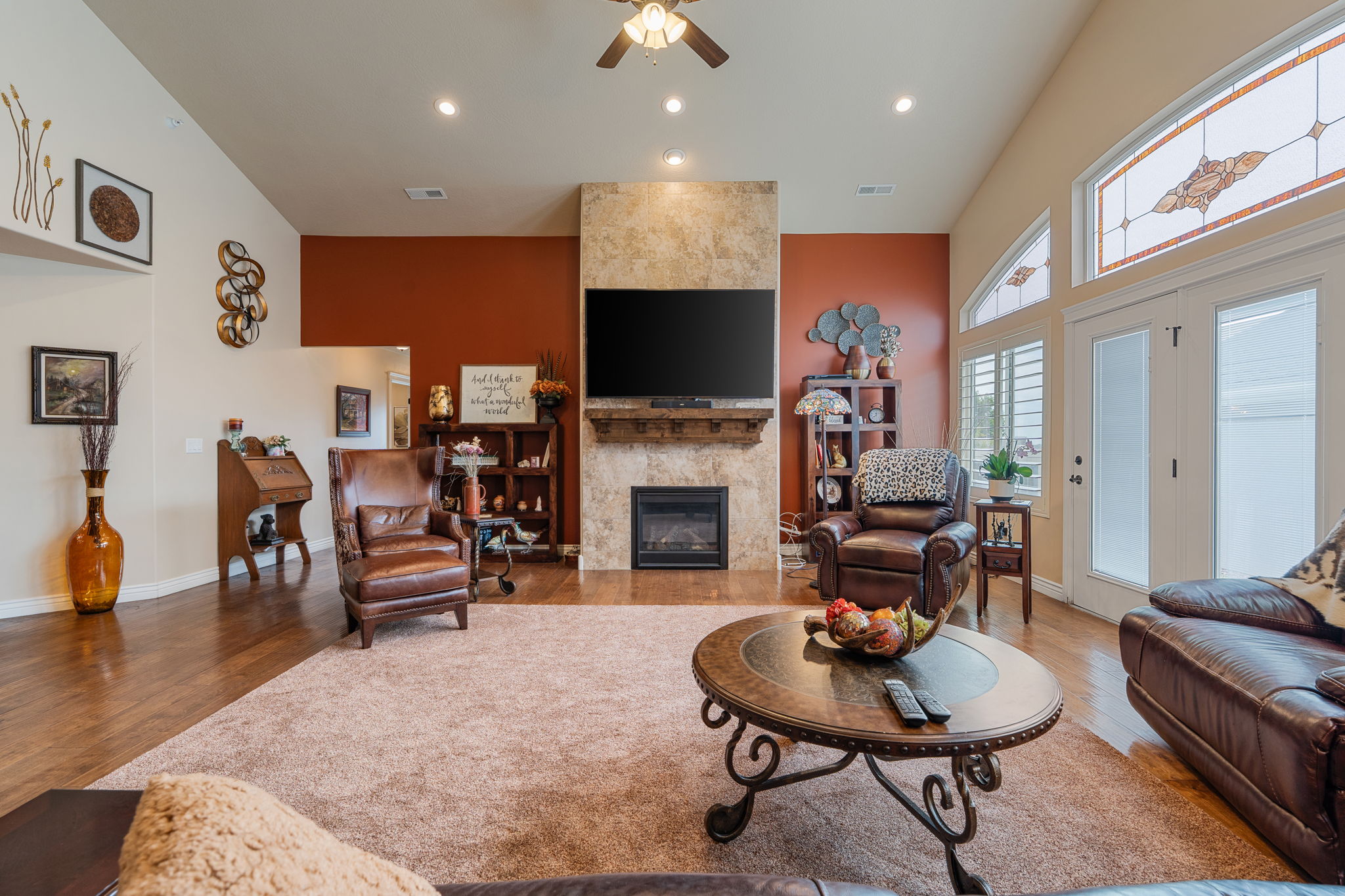 Vaulted ceilings accent this living space featuring a stone-clad fireplace with a wood mantel