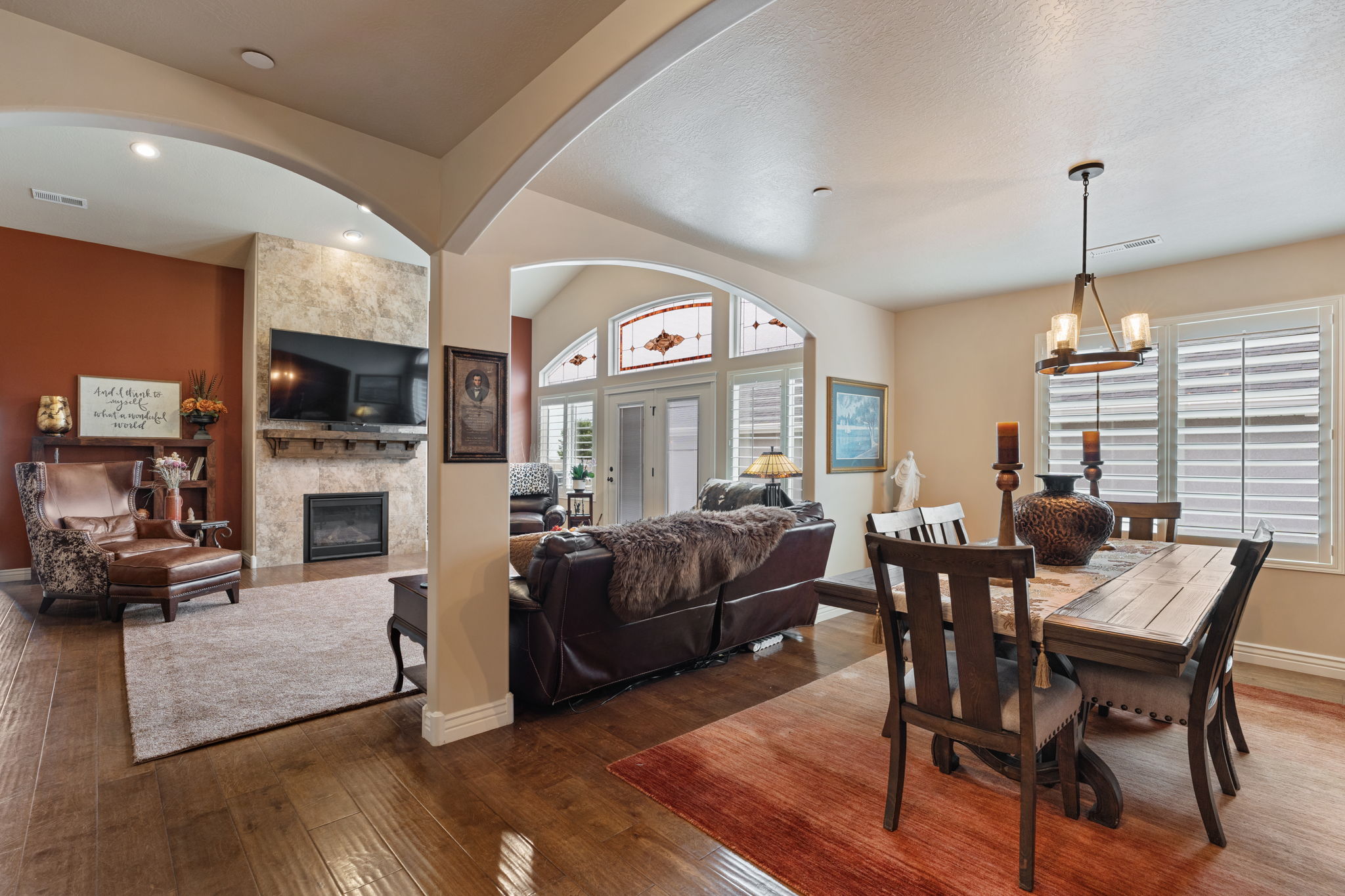 Spacious dining area featuring wood-finish flooring, a contemporary chandelier, and plantation shutters