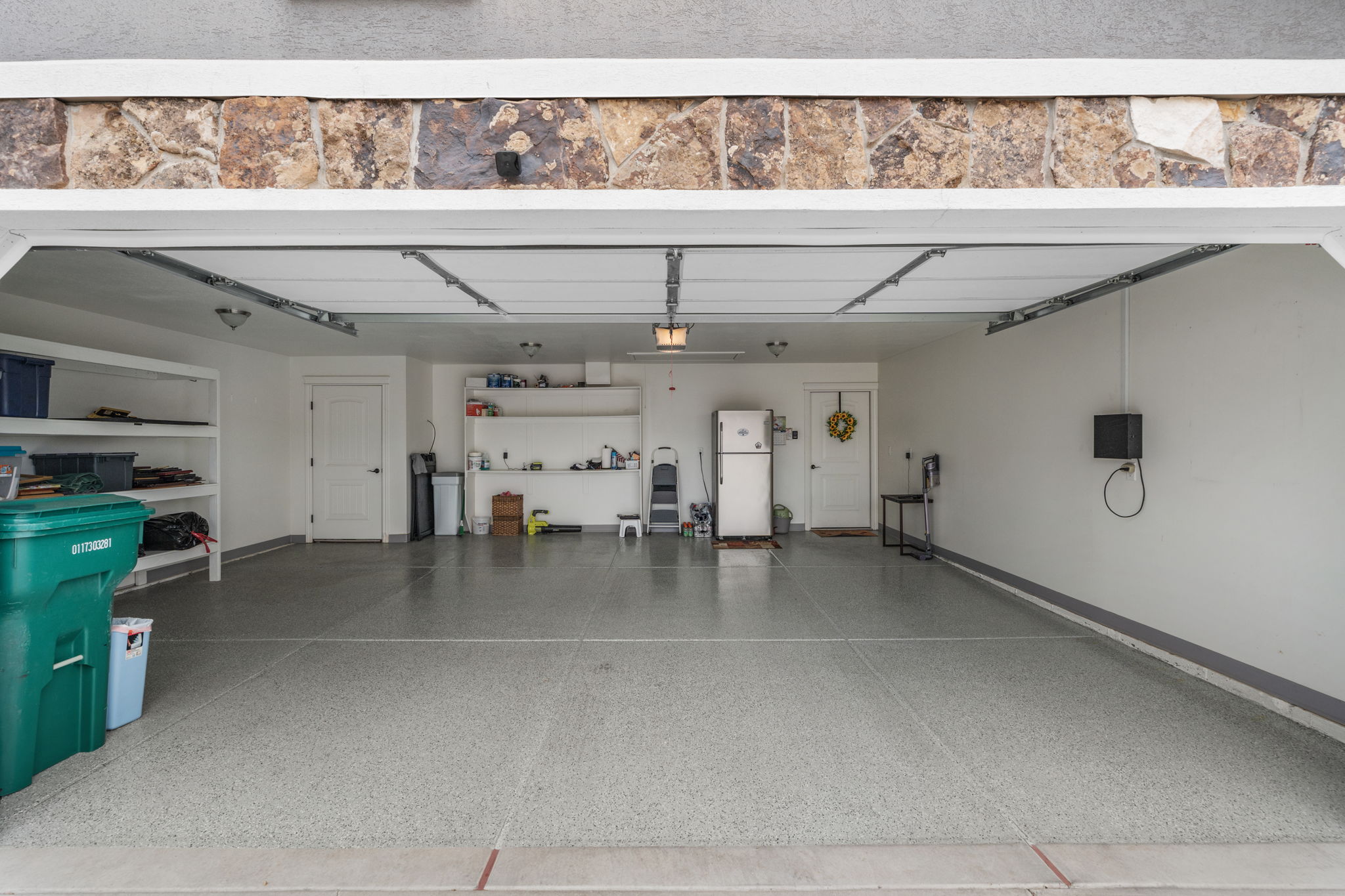 Spacious garage featuring an epoxy-coated concrete floor, white painted walls, and overhead lighting