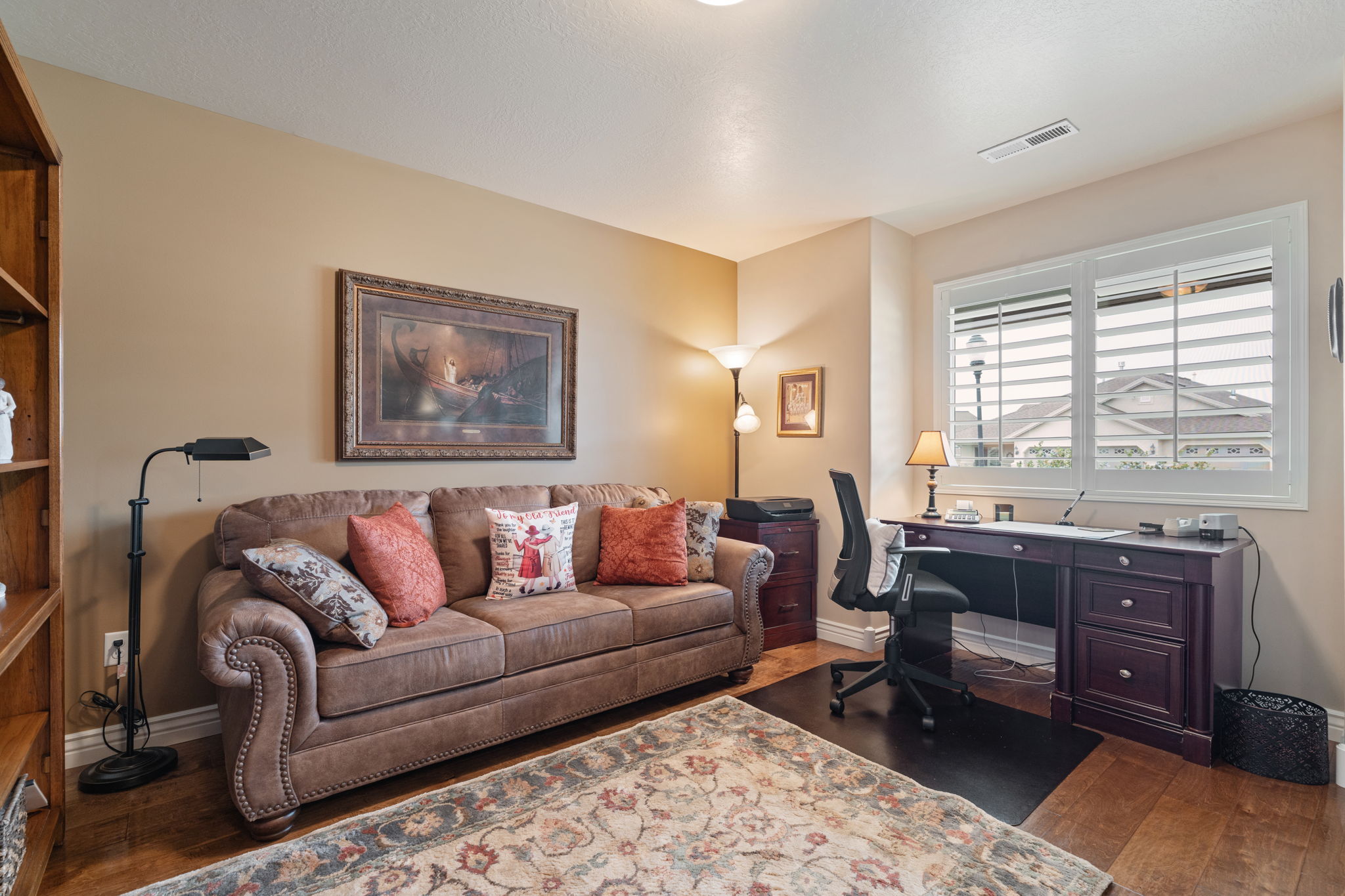 Dedicated room featuring wood-finish flooring, a built-in bookshelf, and a large window with plantation shutters