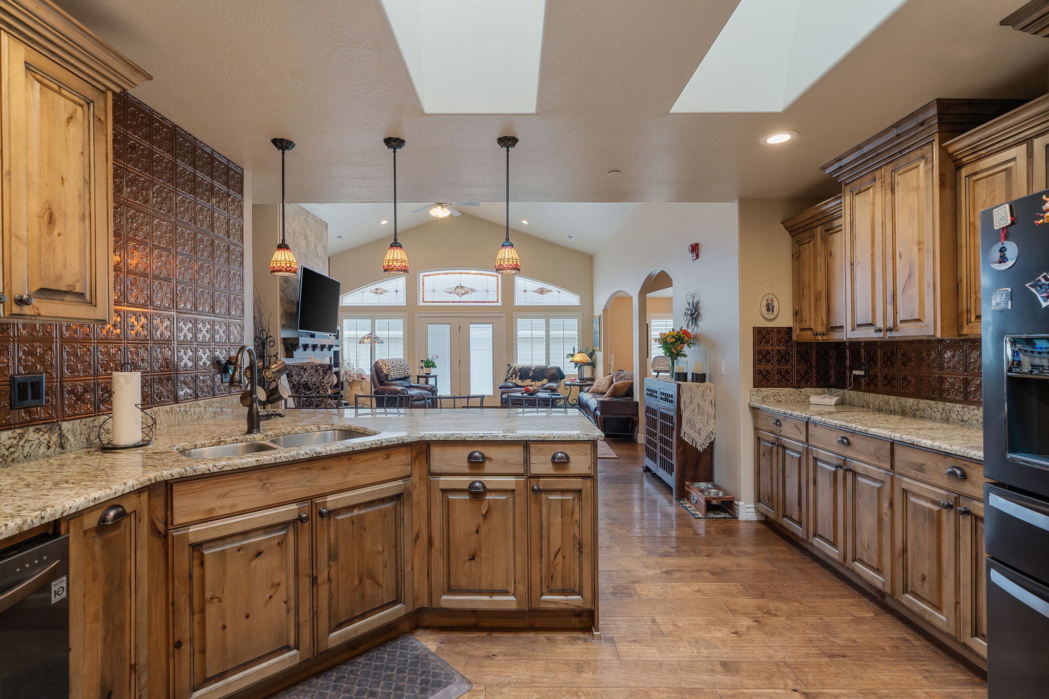 Kitchen featuring wood-finish cabinetry, light-toned granite countertops, and an embossed metal backsplash