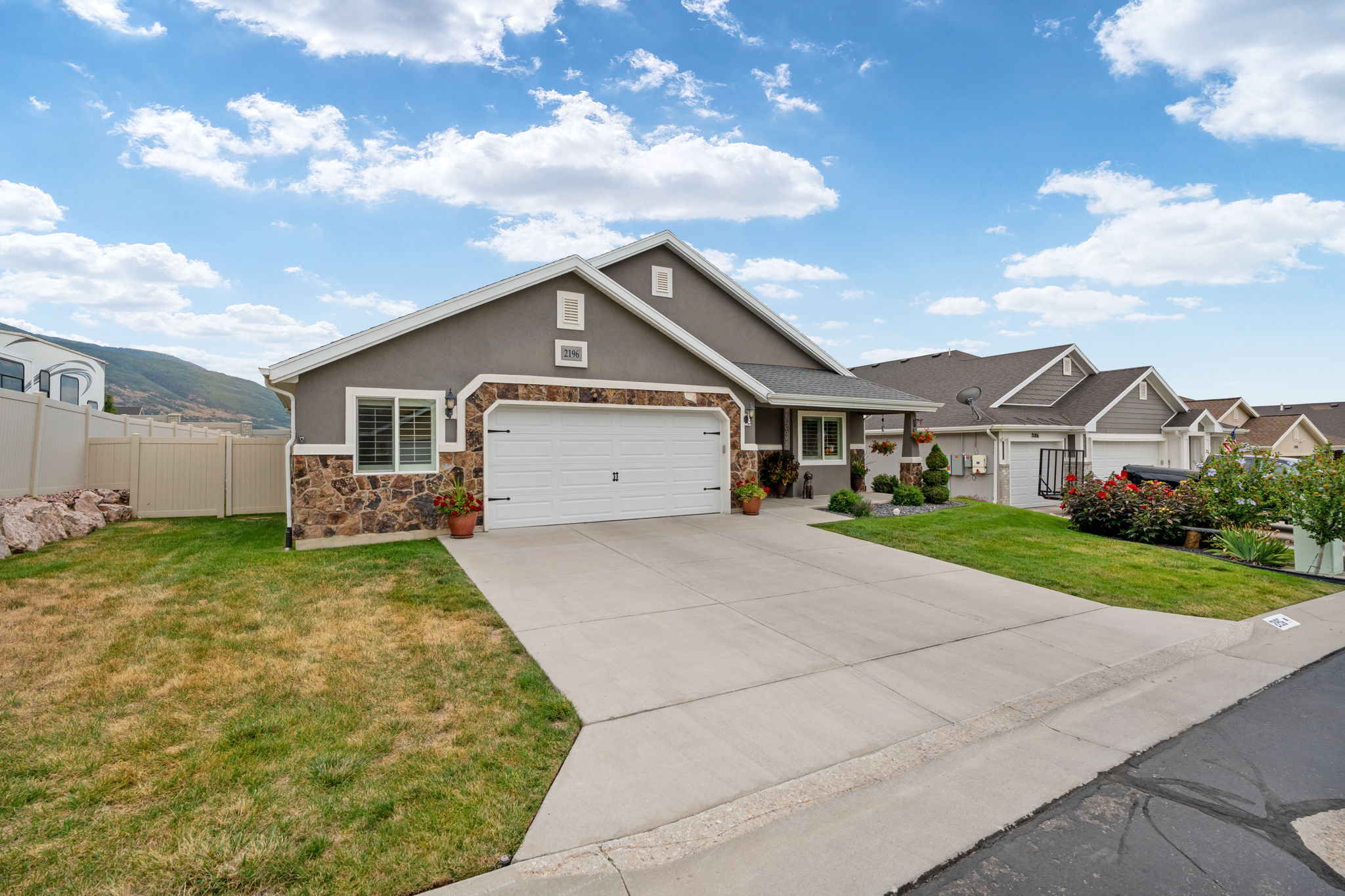 Contemporary ranch-style home featuring a two-car garage, stone and stucco exterior, and a concrete driveway