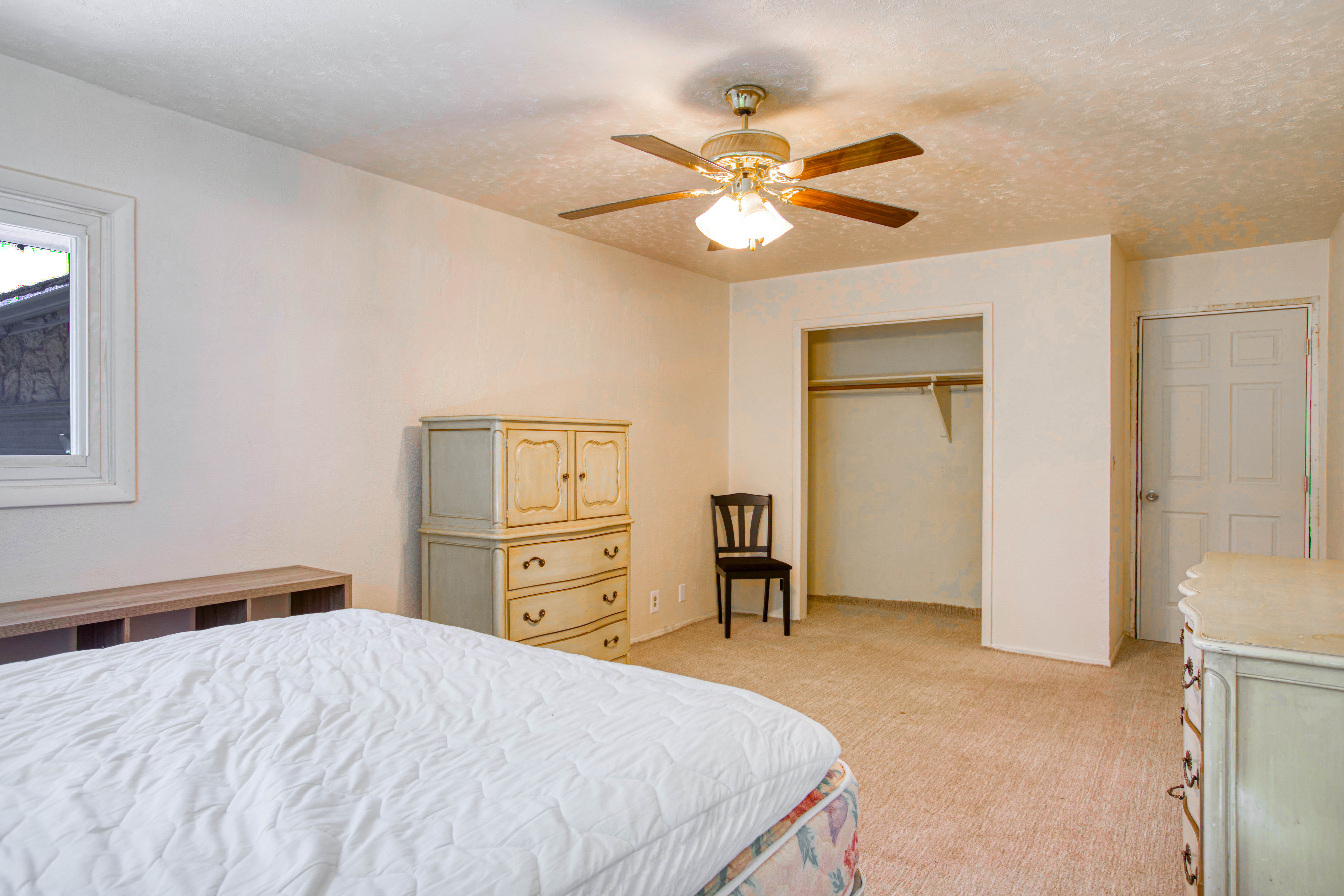 Room featuring neutral wall tones, textured ceiling, a ceiling fan with integrated lighting, and light-toned carpeting