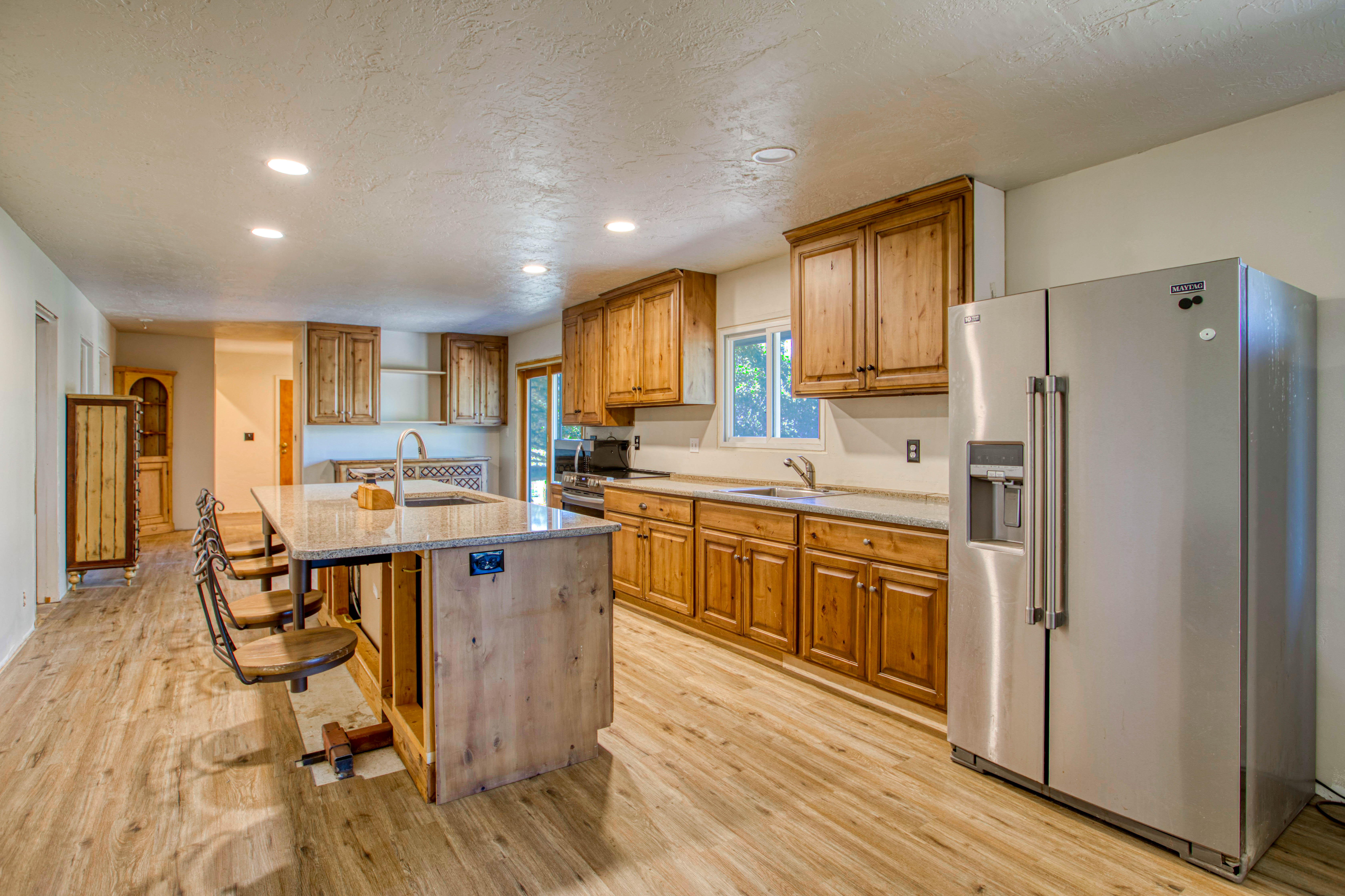 Kitchen featuring a central island with bar seating, wood-finish flooring, recessed lighting, wood cabinetry, and a side-by-side stainless steel refrigerator