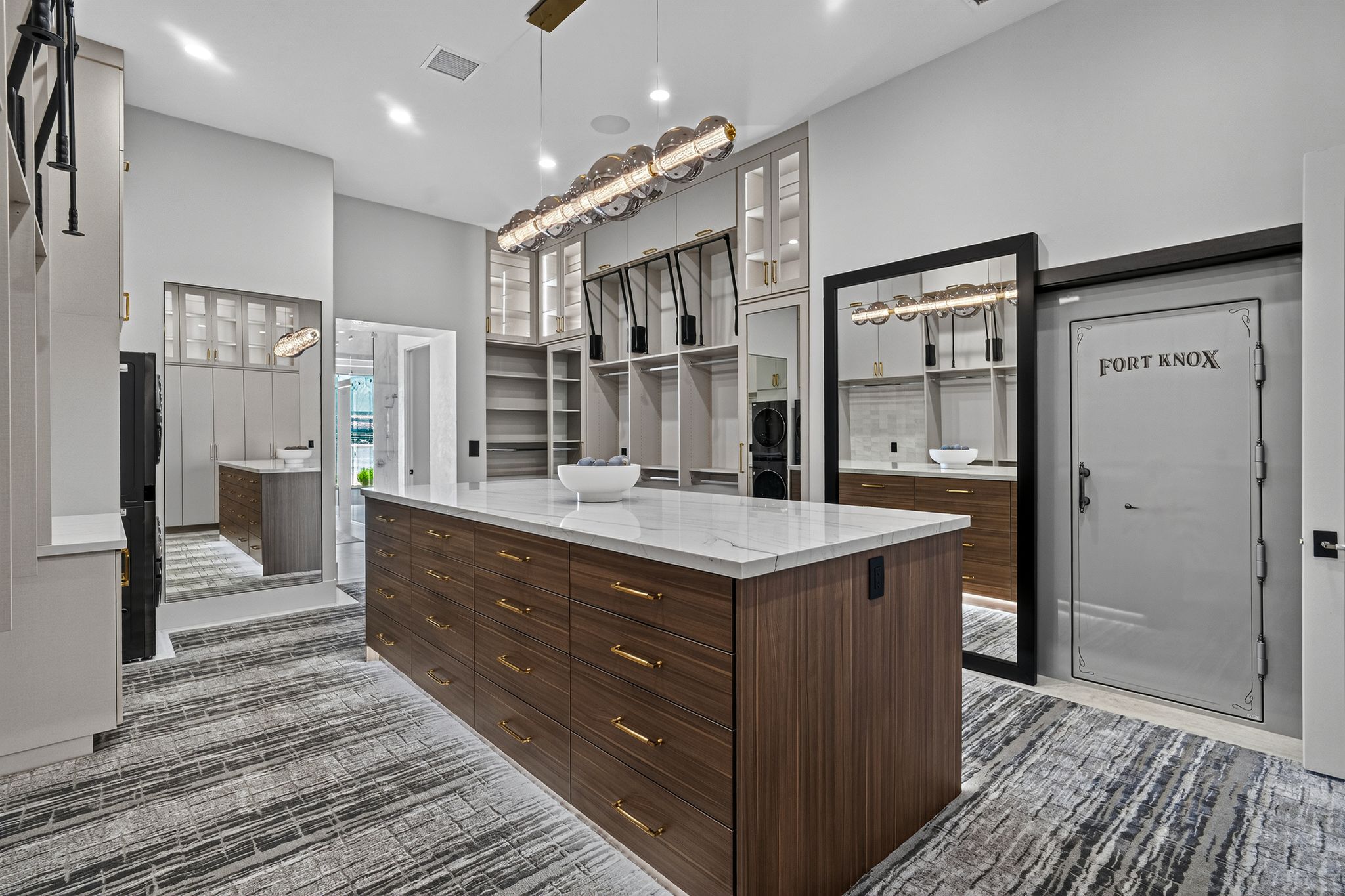 Spacious custom closet featuring a large central island with a stone countertop and wood-finish cabinetry