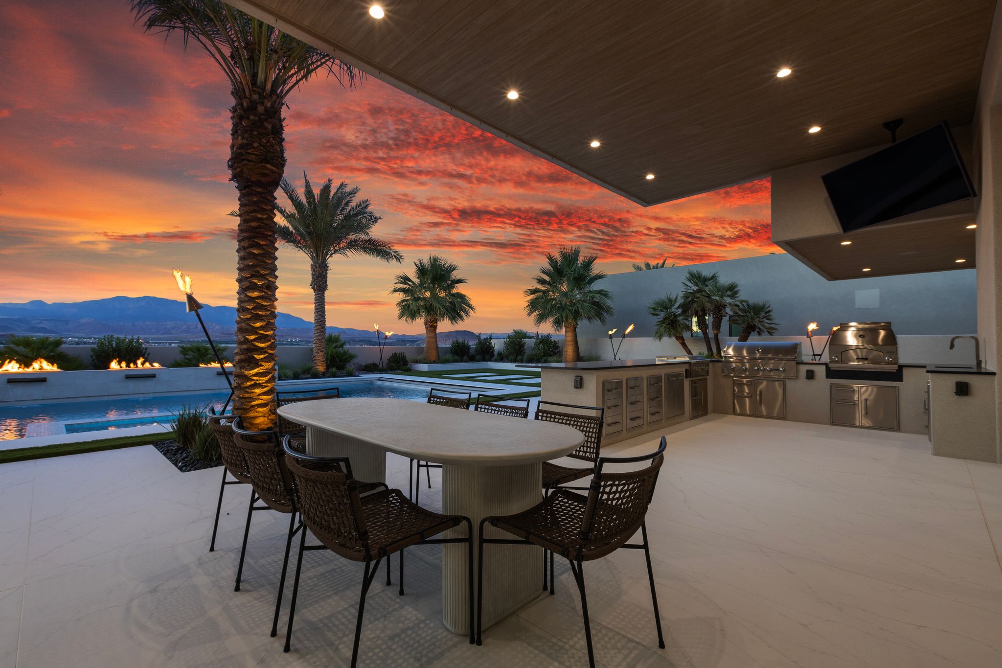 Outdoor living area featuring a covered patio with recessed lighting, an outdoor kitchen with stainless steel appliances, a built-in grill, and a sink