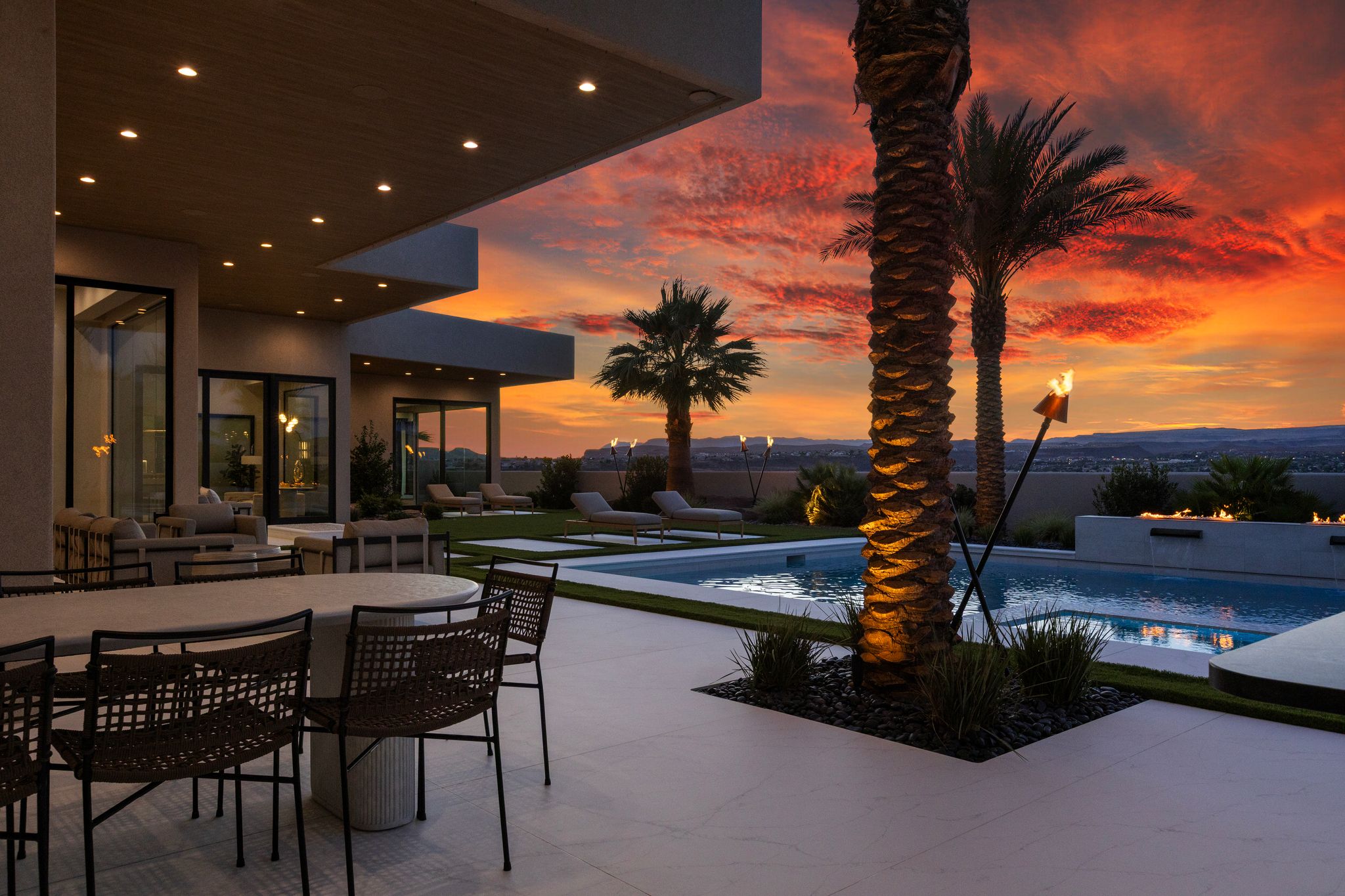 Expansive exterior patio featuring a built-in swimming pool, integrated fire feature, and mature palm trees