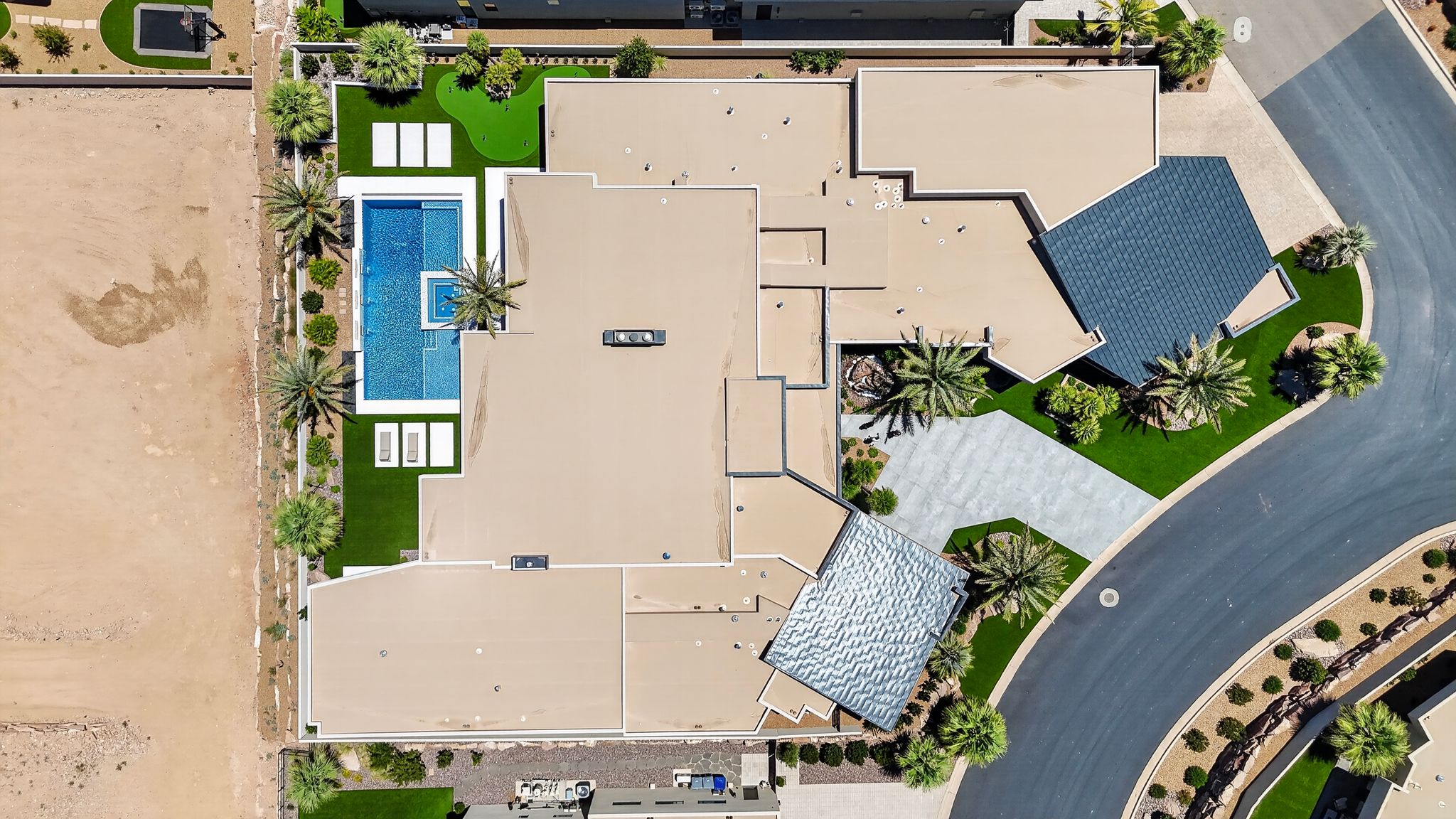 Expansive property featuring a multi-segment swimming pool with integrated spa, surrounding artificial turf landscaping, and mature palm trees