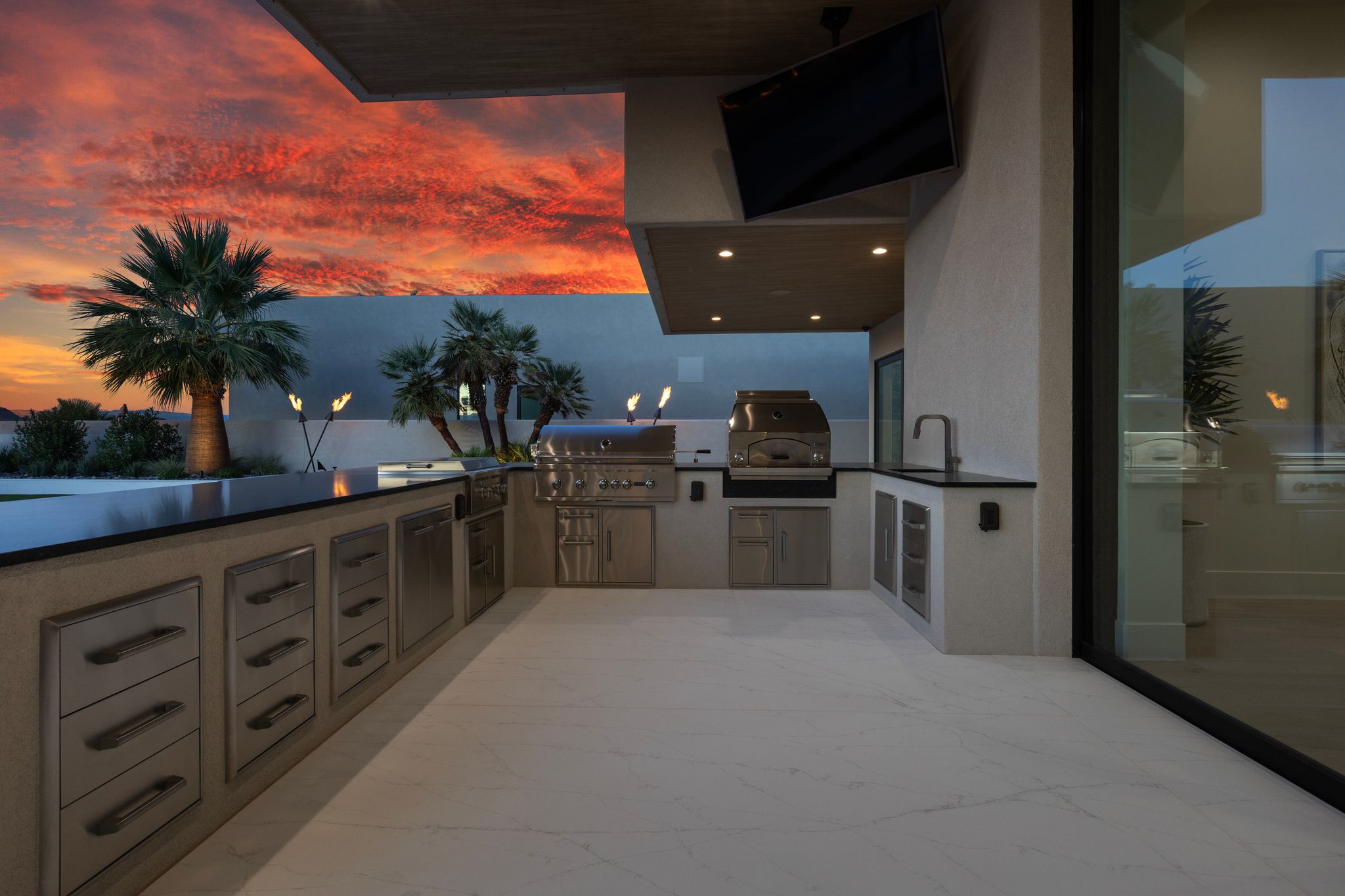 Expansive outdoor kitchen featuring stainless steel appliances, dark countertops, and integrated cabinetry