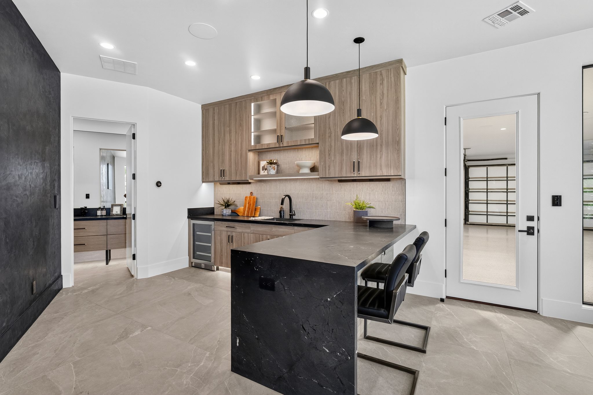 Wet bar featuring light wood-finish cabinetry, dark countertop, and integrated beverage cooler