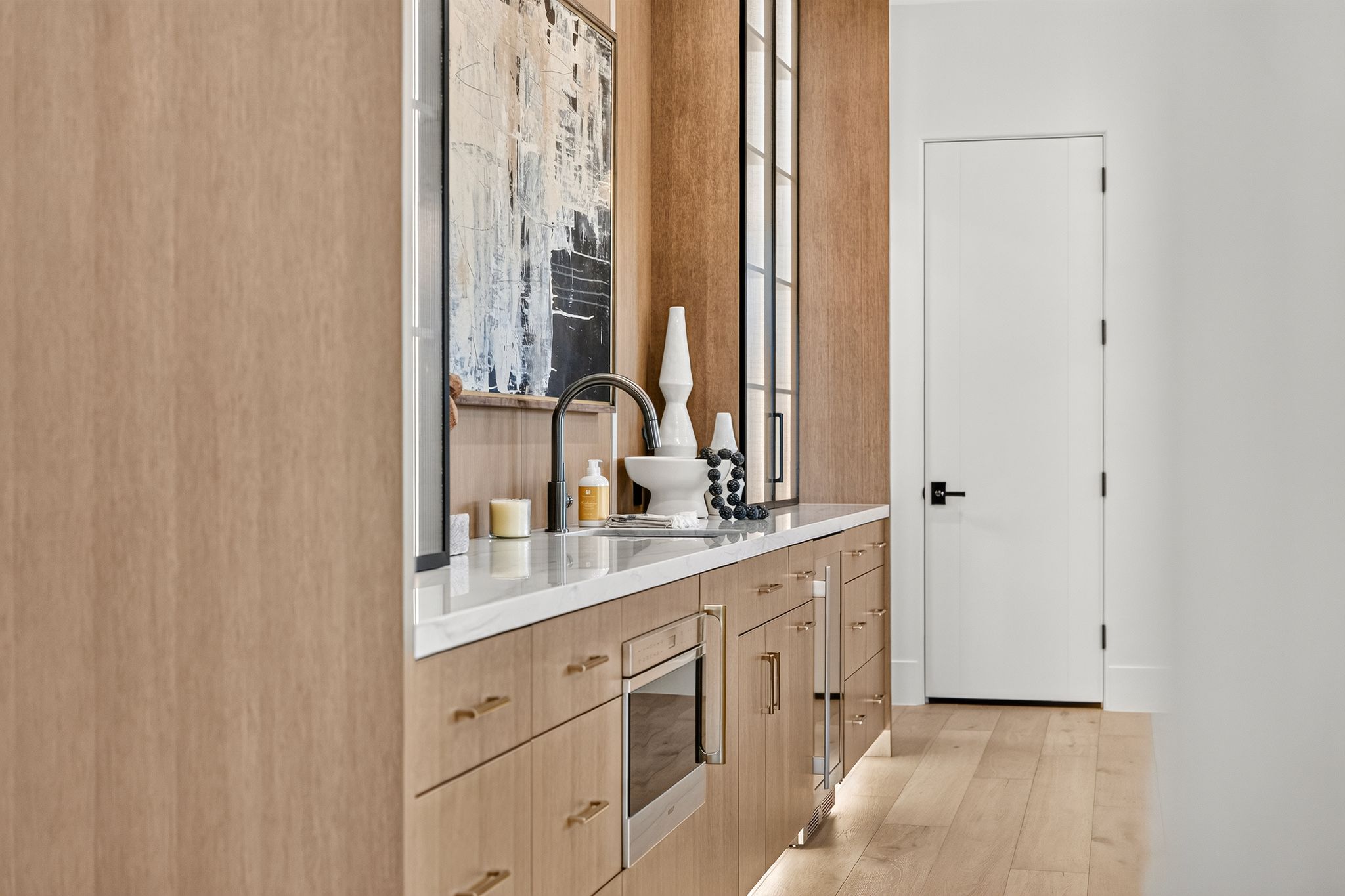Streamlined beverage station featuring wood-finish cabinetry, a white countertop, under-cabinet lighting, and a built-in microwave drawer
