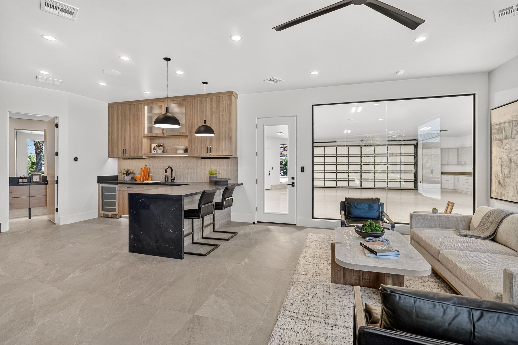Spacious interior featuring large format tile flooring and a built-in wet bar with wood cabinetry and dark stone countertops