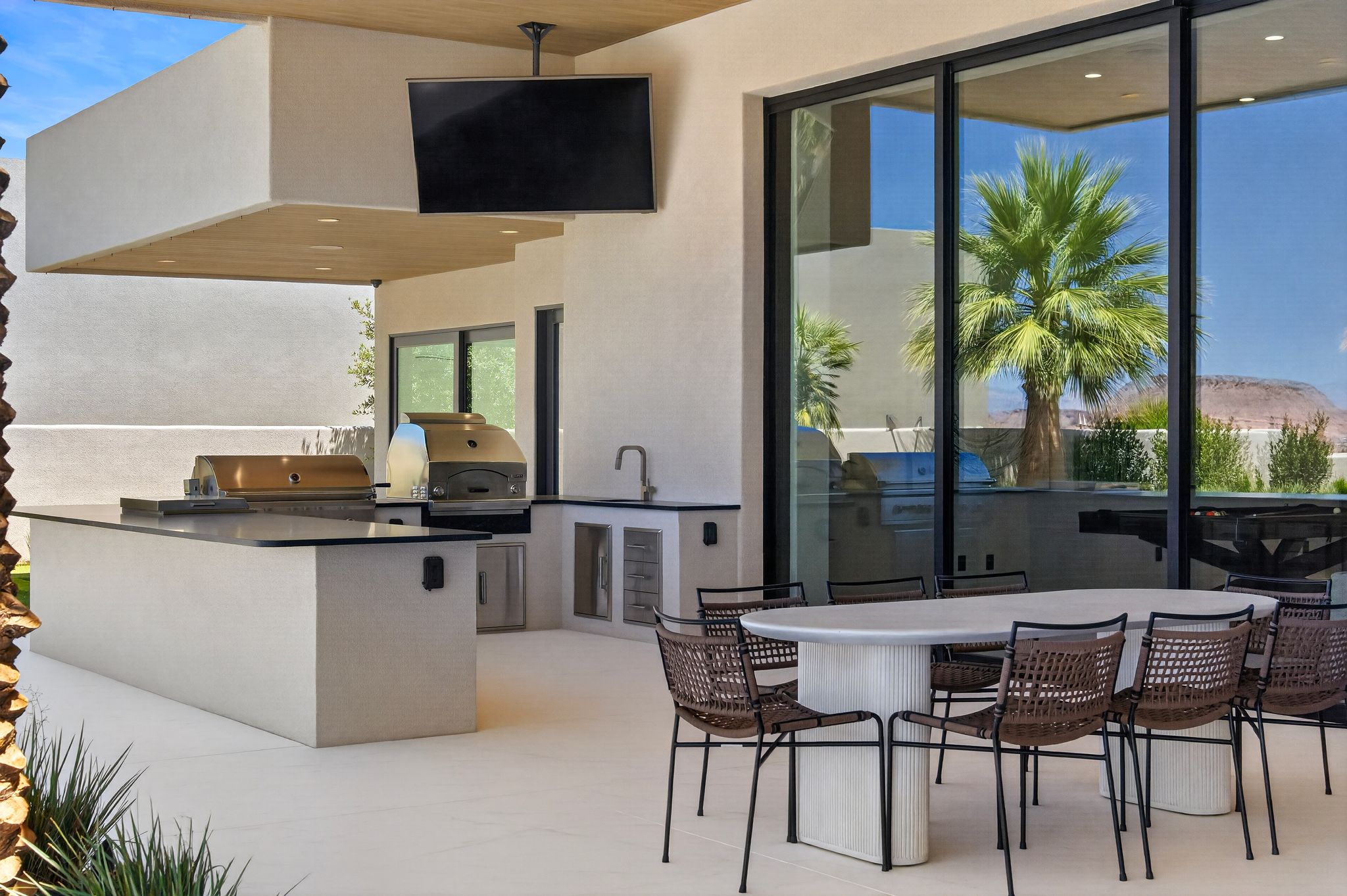 Outdoor kitchen featuring integrated stainless steel appliances, dark countertops, and a built-in sink
