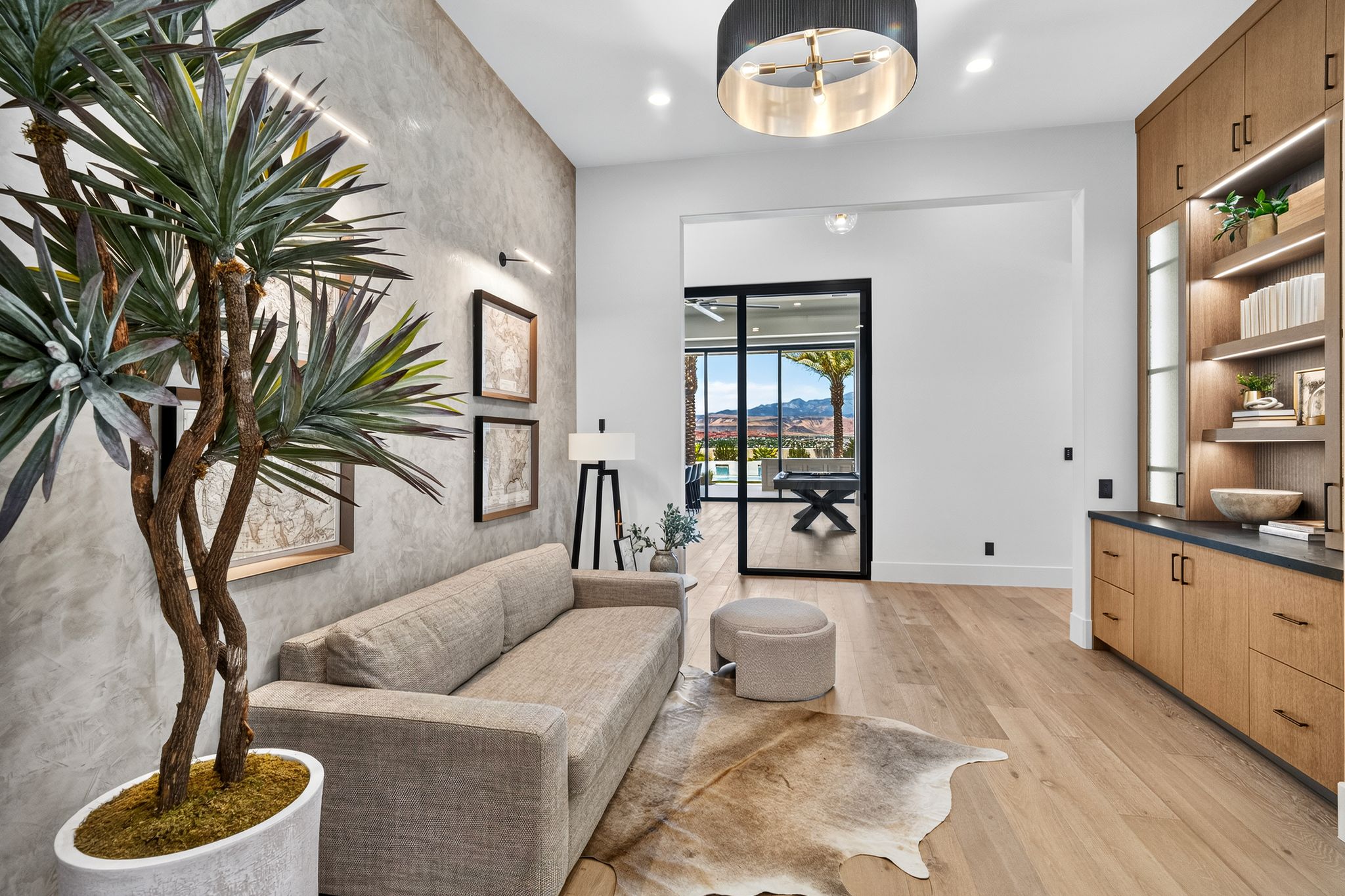 Interior space featuring wood-finish flooring, a textured accent wall, and a built-in cabinetry unit with integrated lighting and a dark countertop