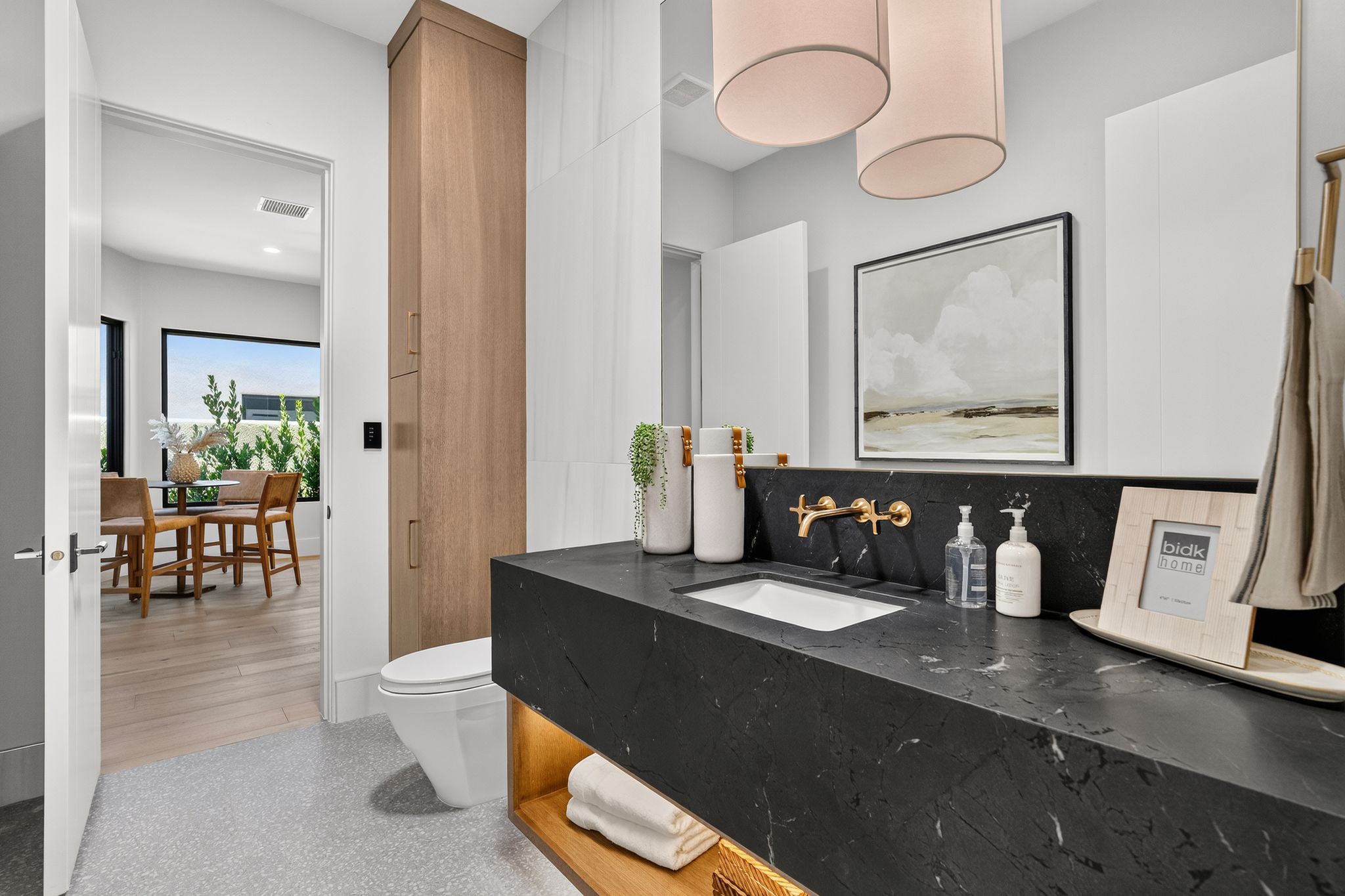 Modern vanity with a dark stone countertop and integrated sink, featuring a wall-mounted brass faucet