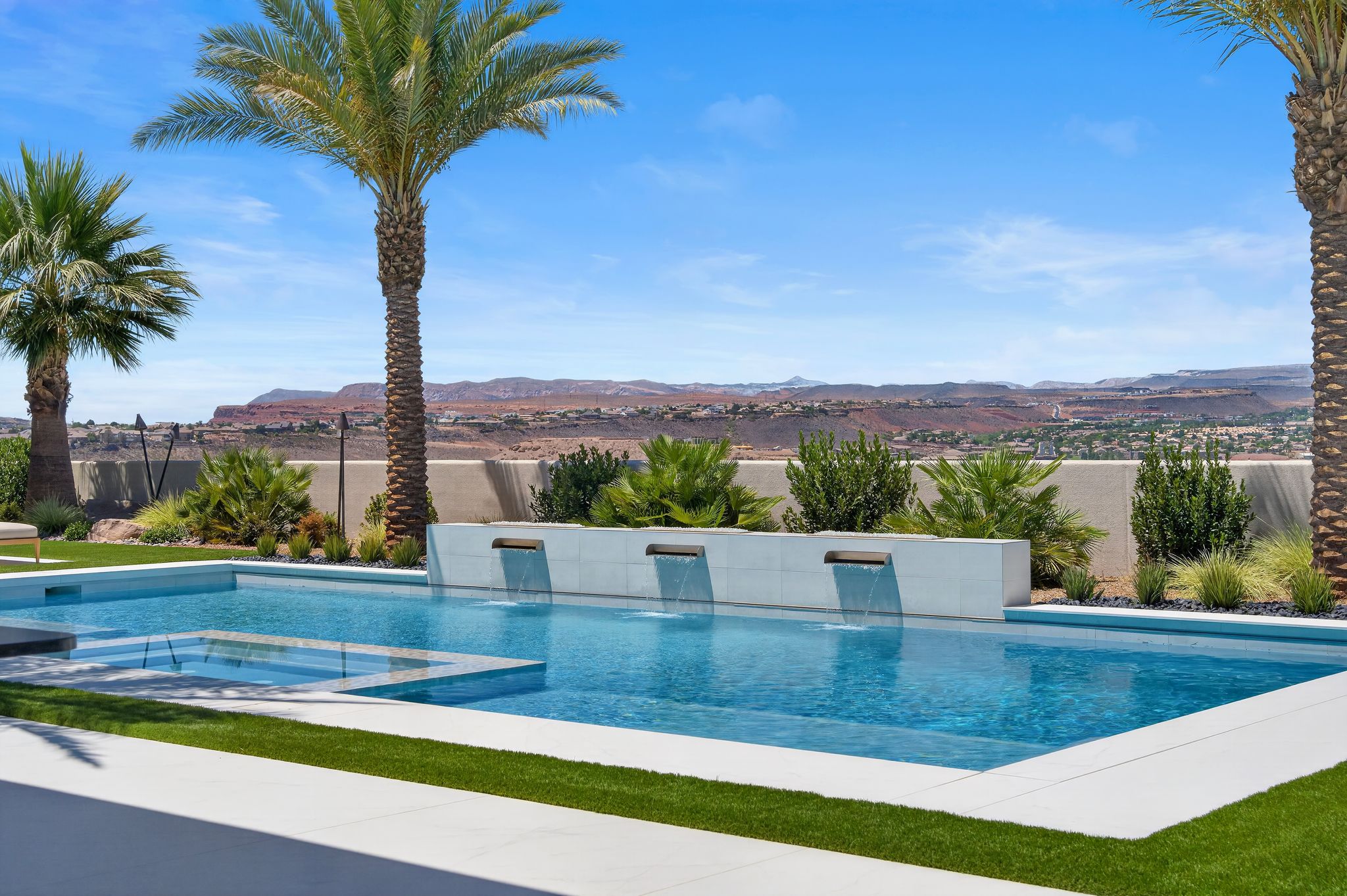 Outdoor swimming pool with integrated spa, featuring multiple cascading water features