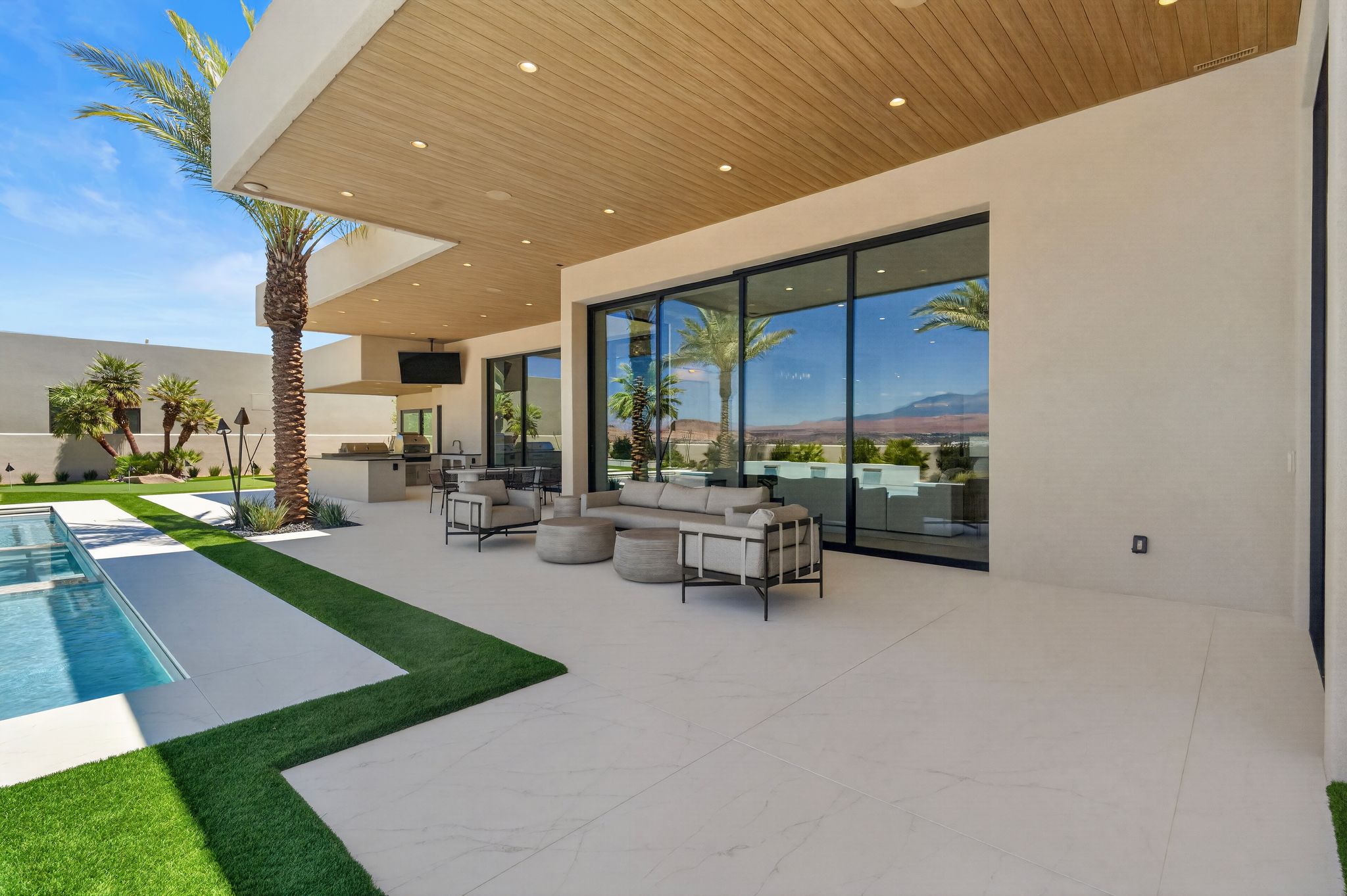 Expansive outdoor living area featuring a large swimming pool, integrated artificial turf sections, and a spacious patio with large format tile