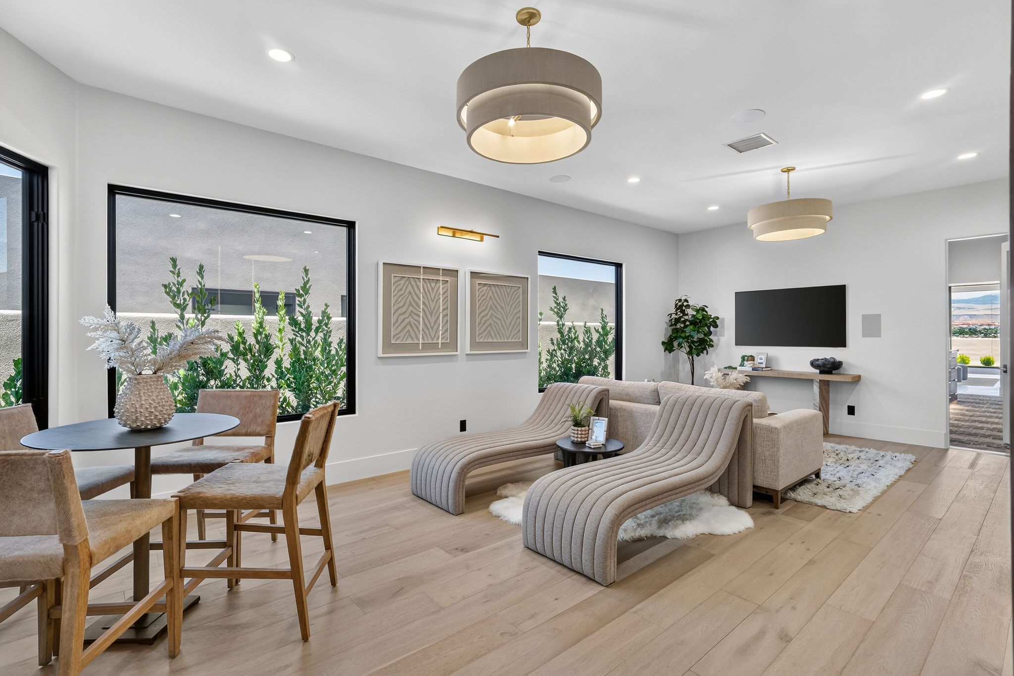 Open-concept living area featuring light wood-finish flooring, recessed lighting, and modern pendant fixtures