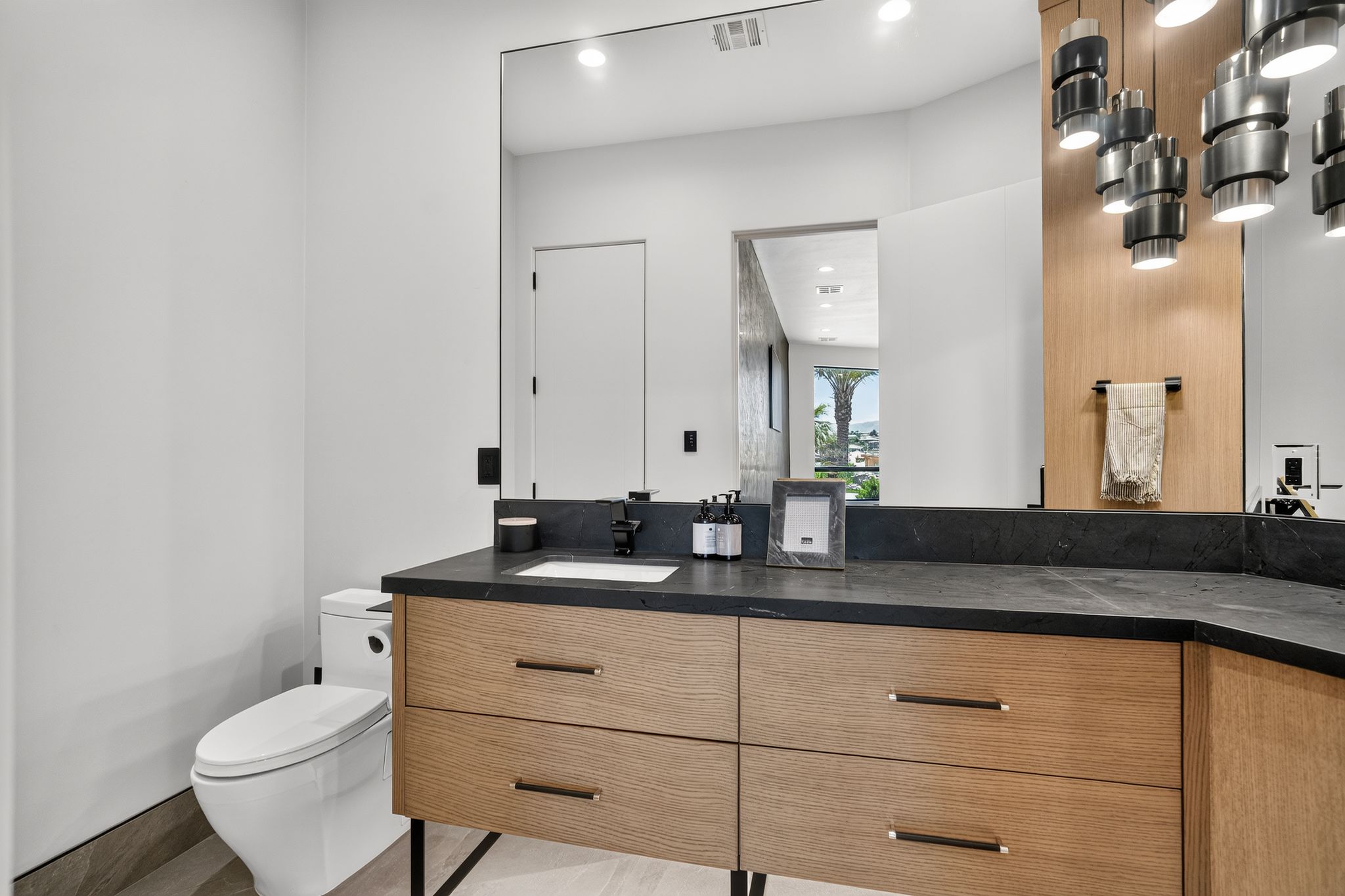 Modern bathroom vanity featuring a dark countertop with an integrated sink and light wood-finish cabinetry