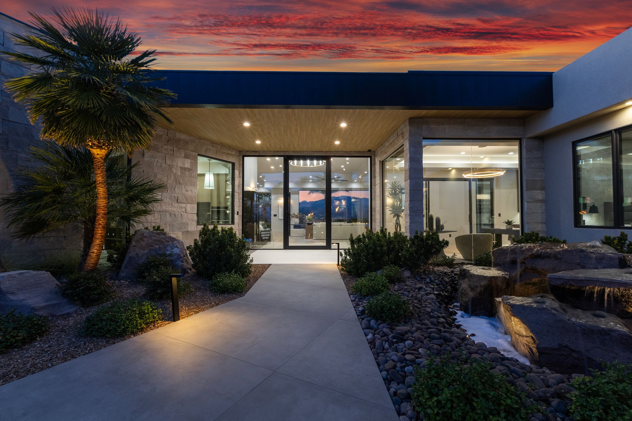 Modern architectural exterior with extensive glass paneling, stone accents, and a distinctive wood-finish soffit