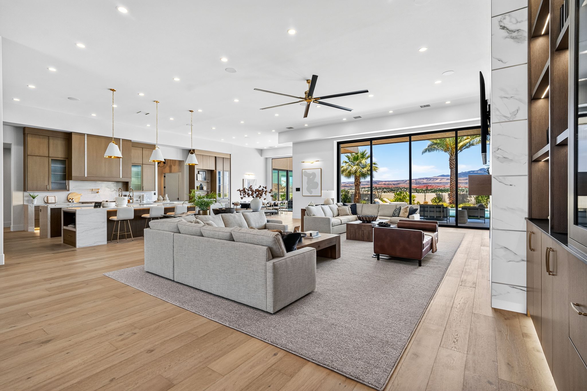 Open-concept living space featuring wood-finish flooring, a large area rug, and a modern ceiling fan