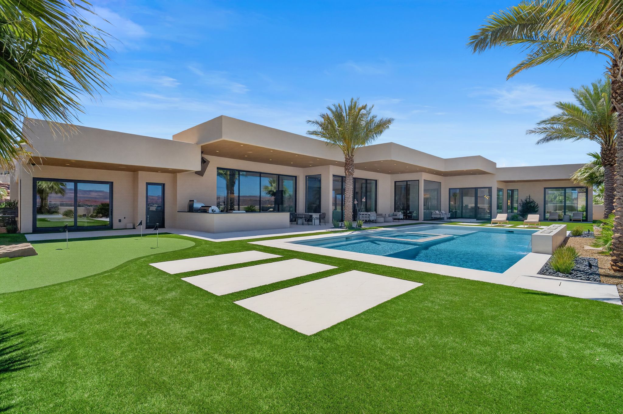 Contemporary residence featuring an expansive backyard with a built-in pool, integrated spa, and artificial turf putting green