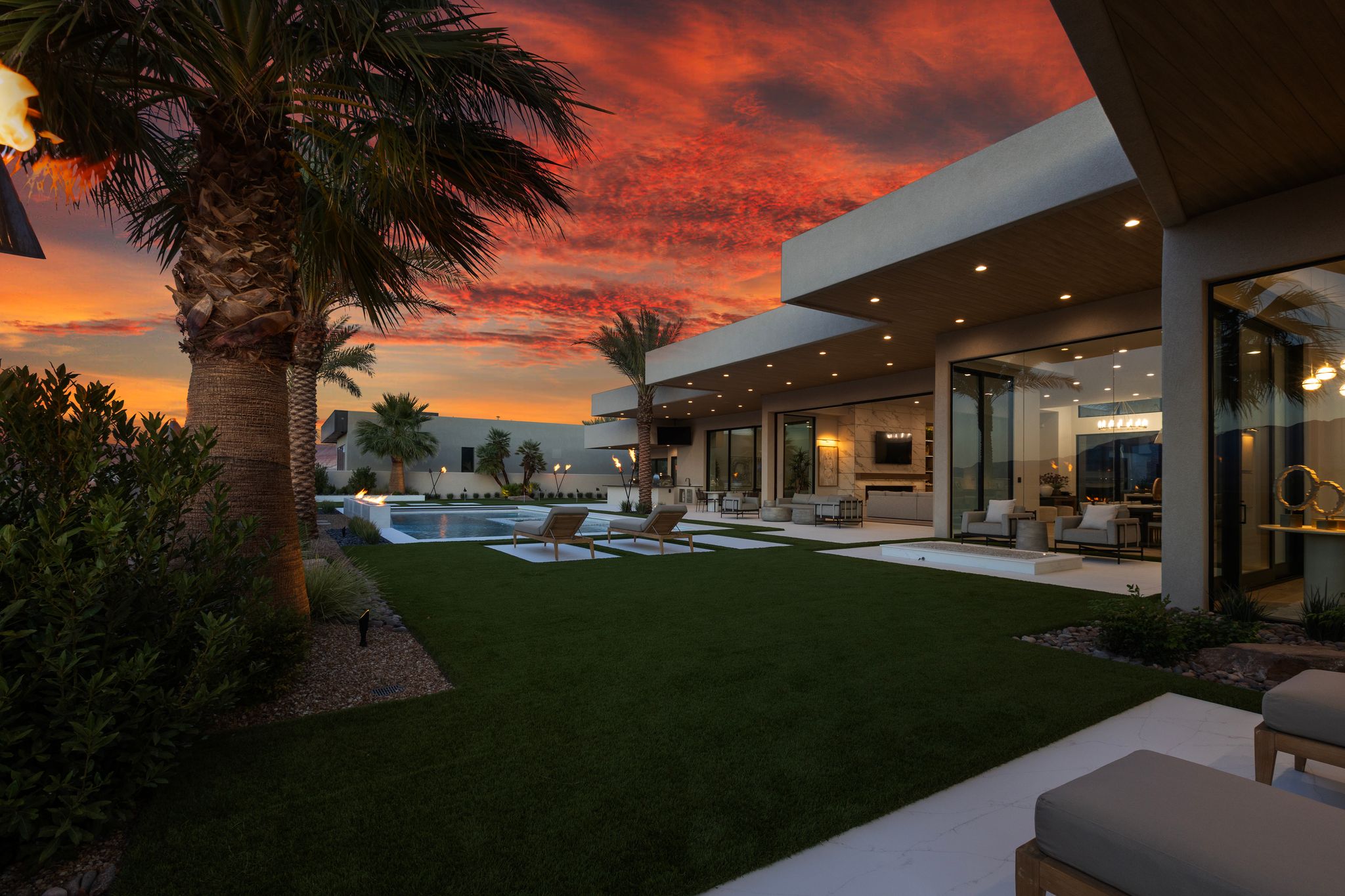 Modern exterior architecture featuring a geometric swimming pool, extensive patio space, and a well-maintained lawn