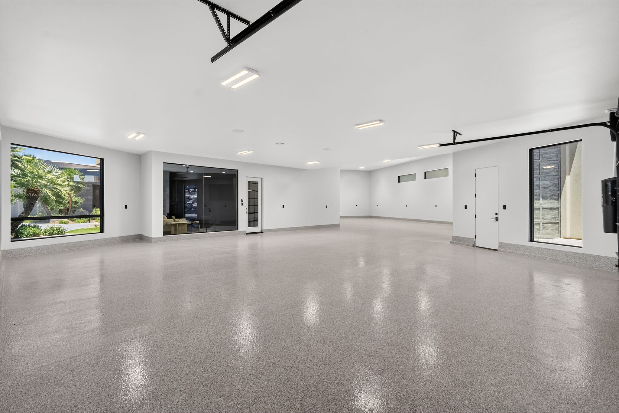 Spacious multi-car garage featuring a speckled epoxy floor, multiple large windows, and recessed lighting