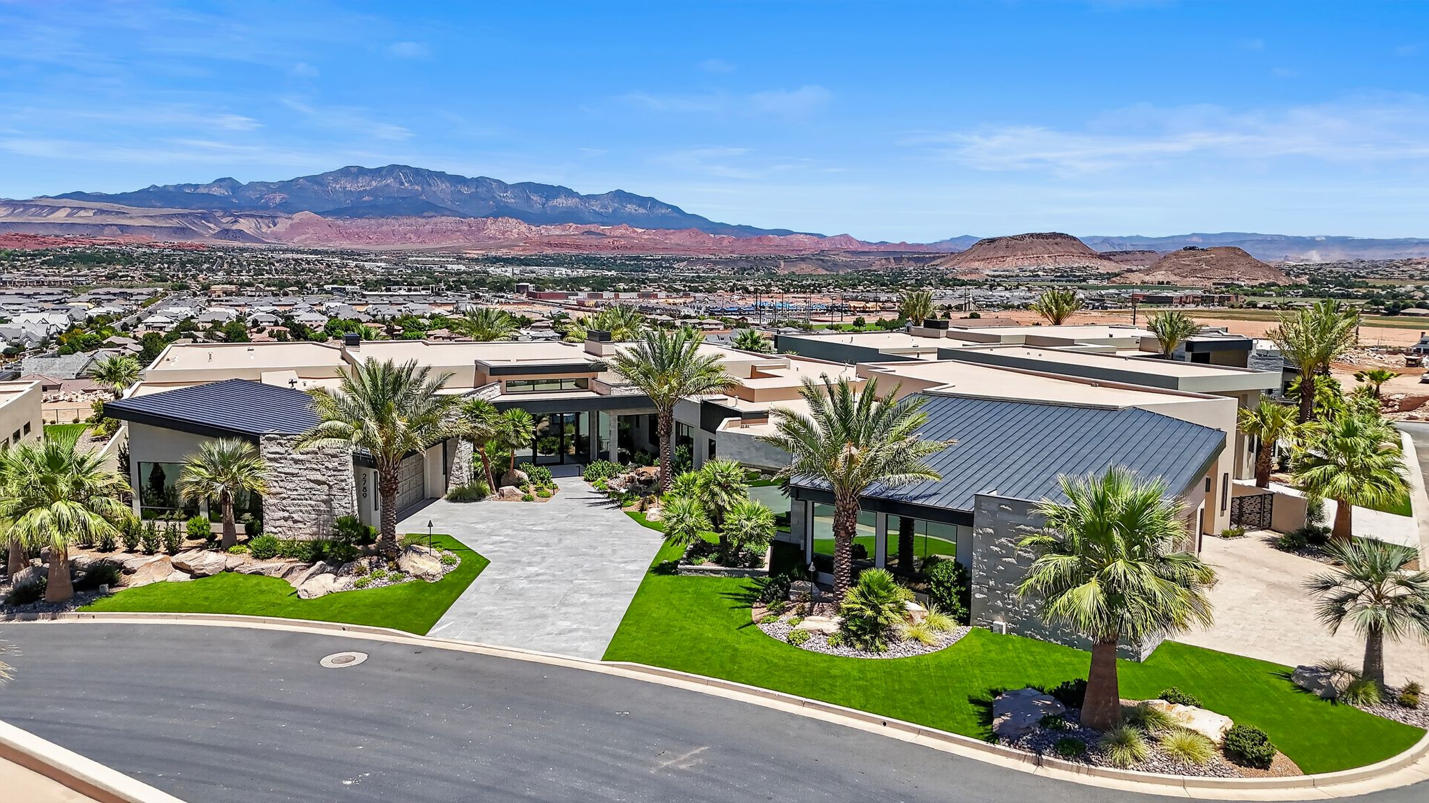Contemporary residence featuring multiple rooflines, stone accents, and a paver driveway