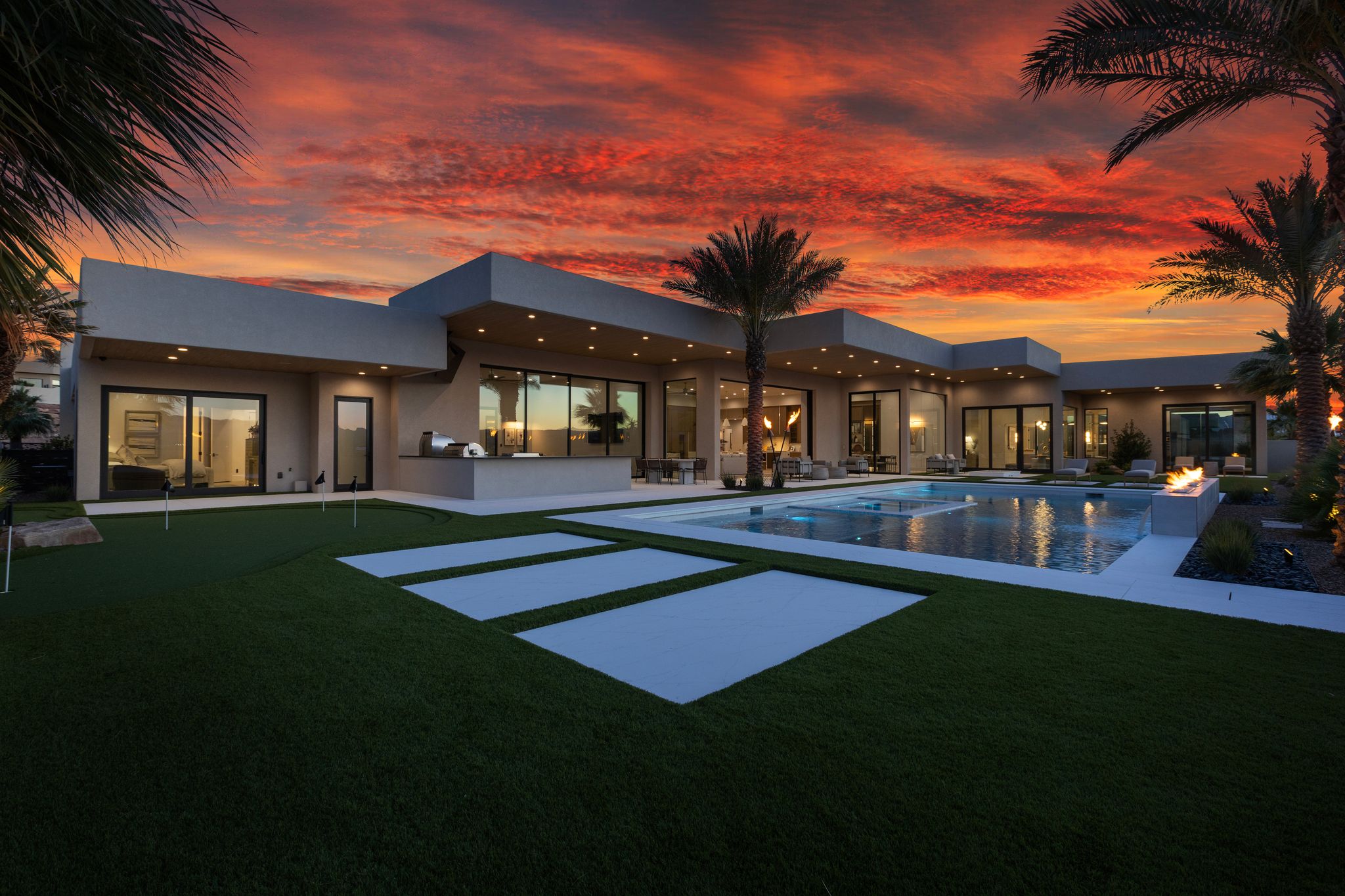 Contemporary exterior with expansive artificial turf, a putting green, and large format patio pavers