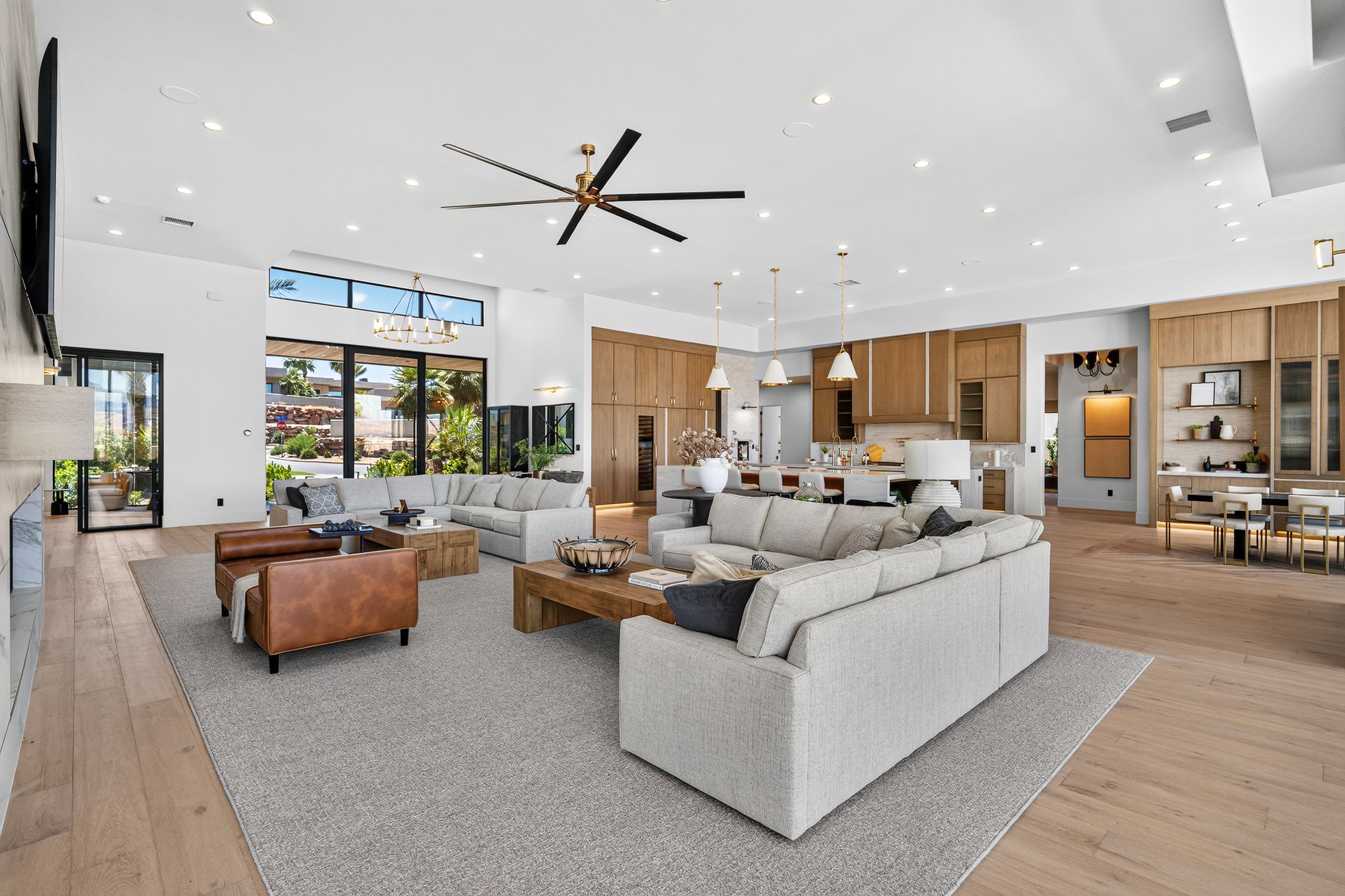 Expansive open-concept interior featuring light wood-finish flooring, recessed lighting, and a contemporary ceiling fan