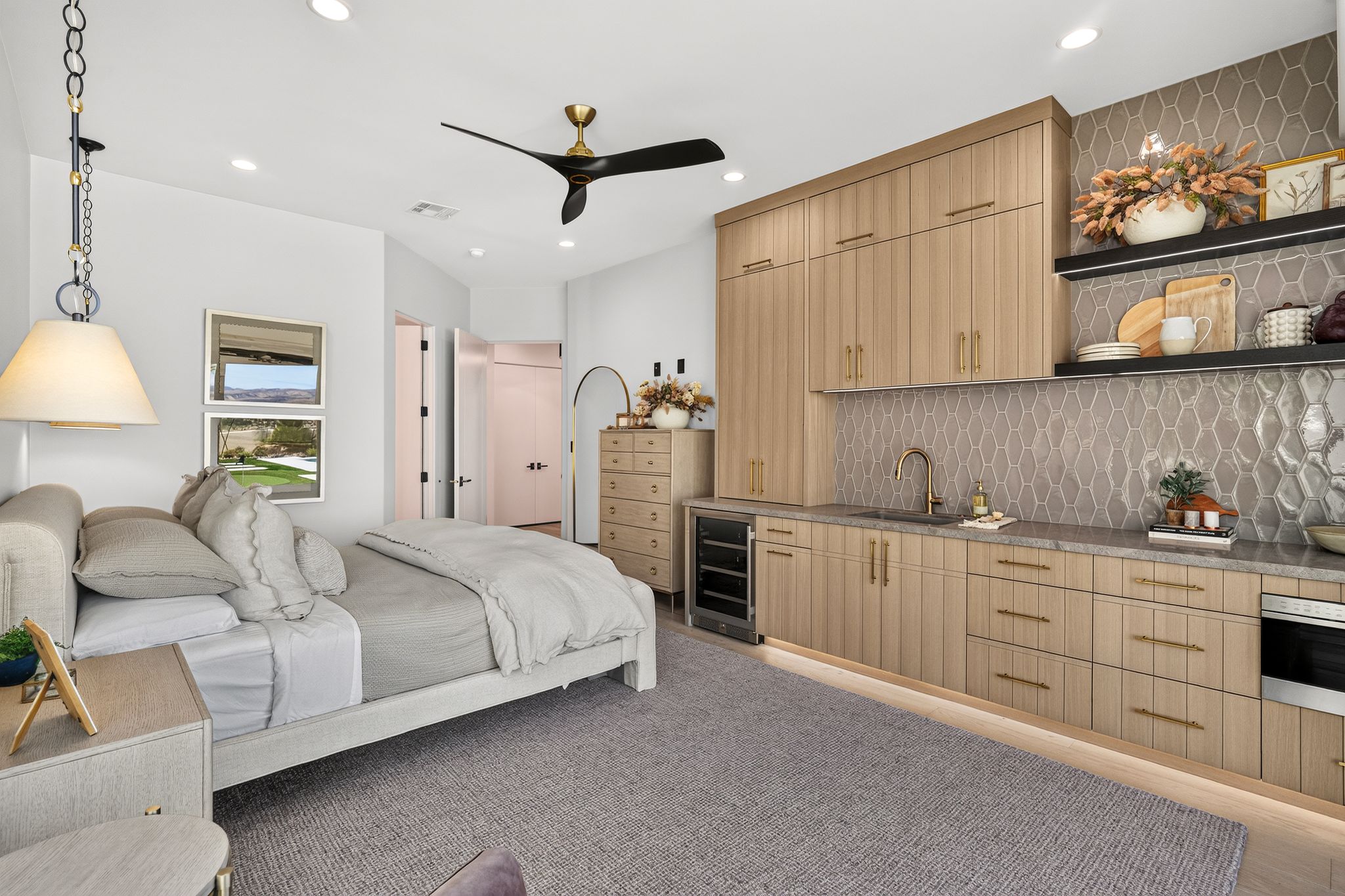 Integrated kitchenette featuring light wood-finish cabinetry, a single basin sink, and a beverage refrigerator