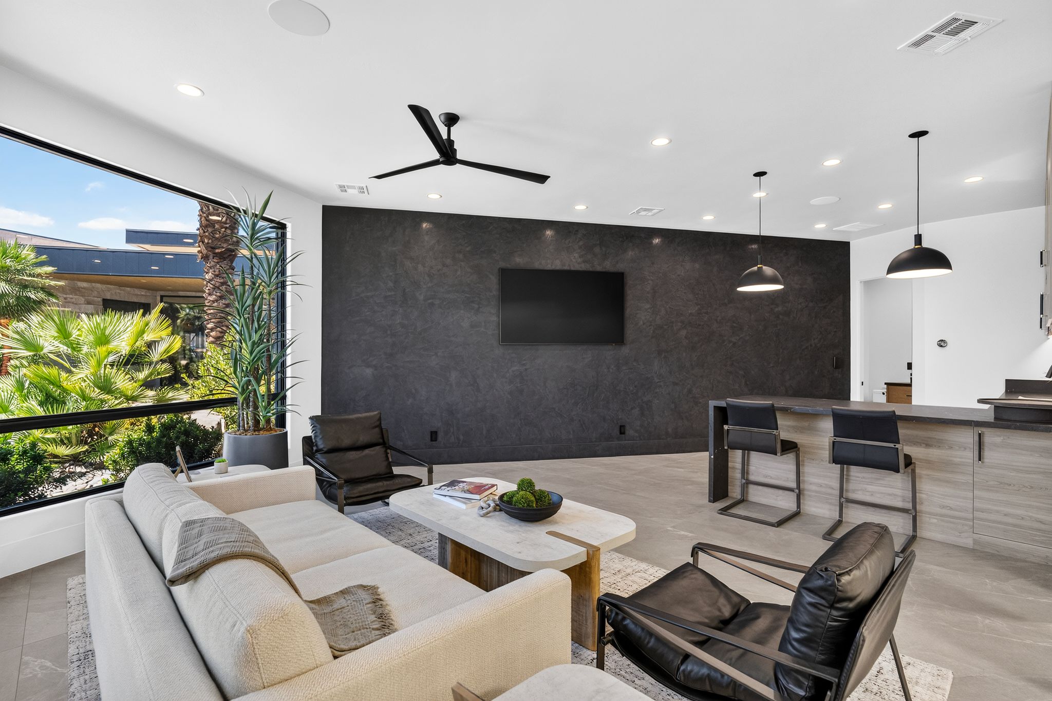 Open-concept living area featuring a large picture window, a textured accent wall, recessed lighting, and a modern ceiling fan