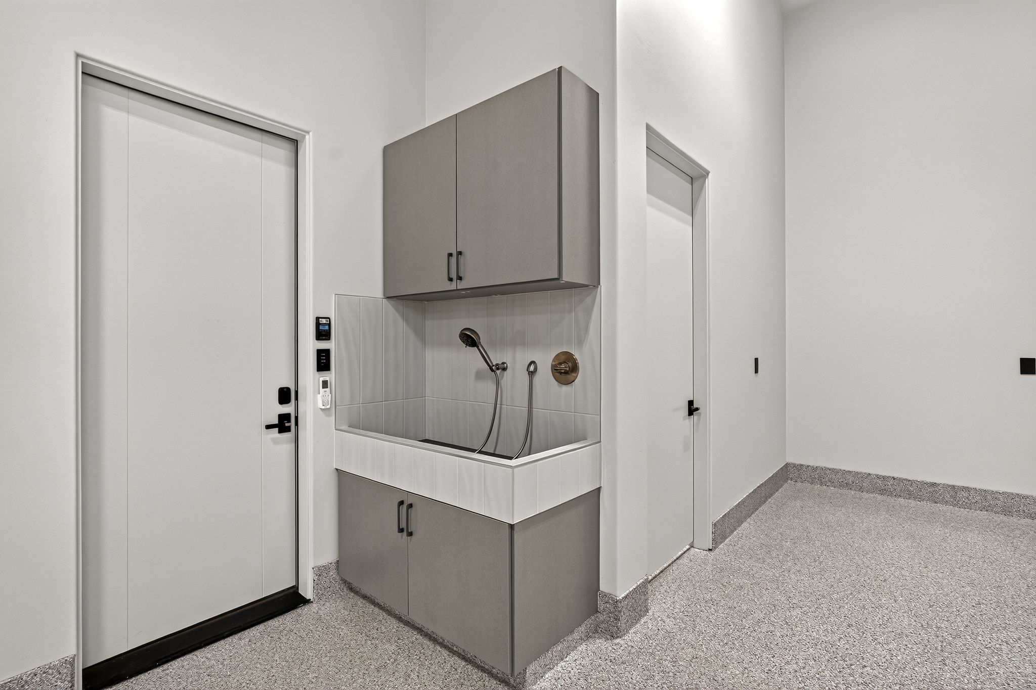 Dedicated utility area featuring a built-in wash station with a handheld sprayer, overhead cabinetry, and lower storage