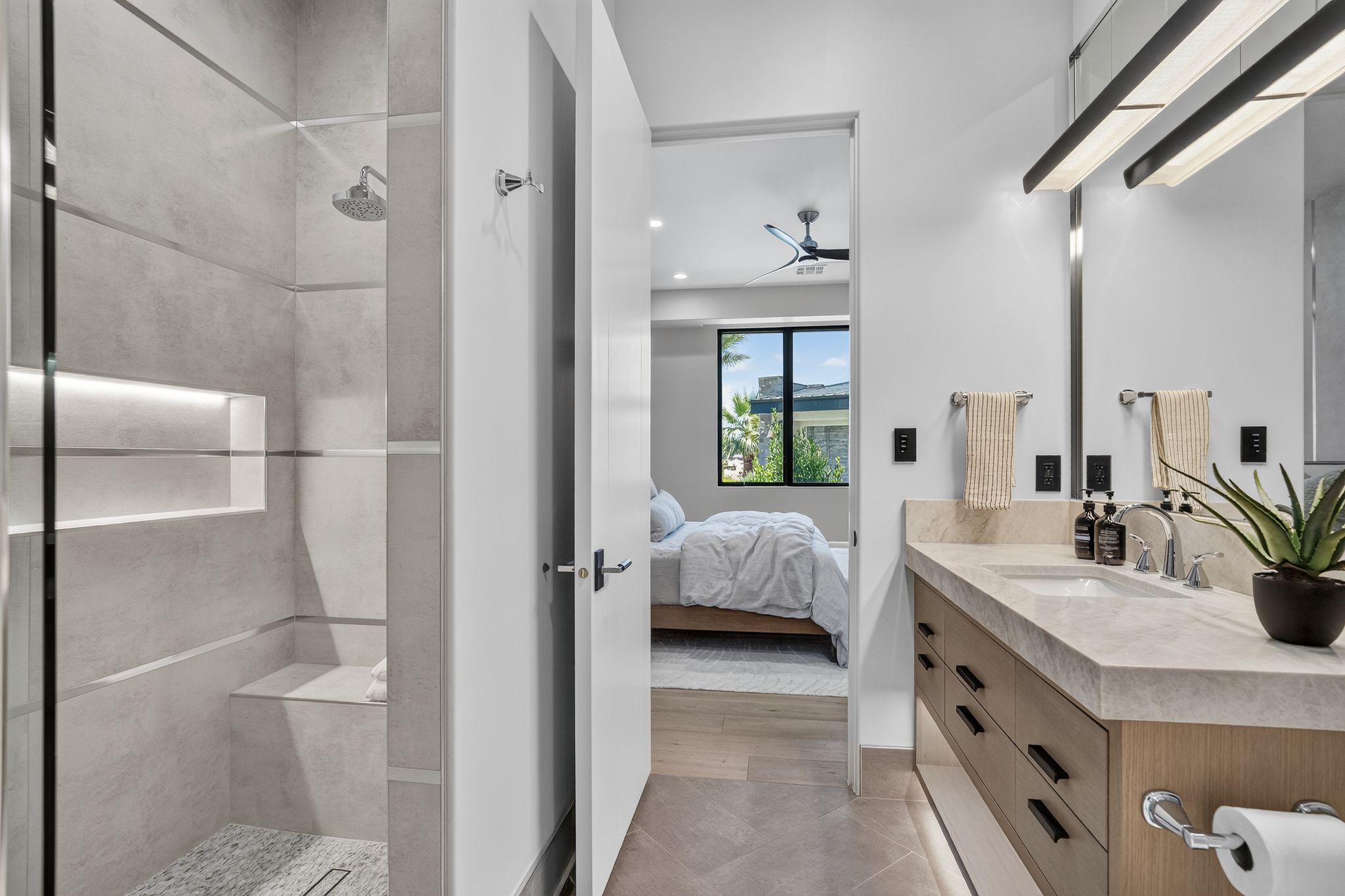 Full bathroom featuring a glass-enclosed shower with a built-in bench and recessed shelving, a single vanity with stone countertop, and wood-finish cabinetry