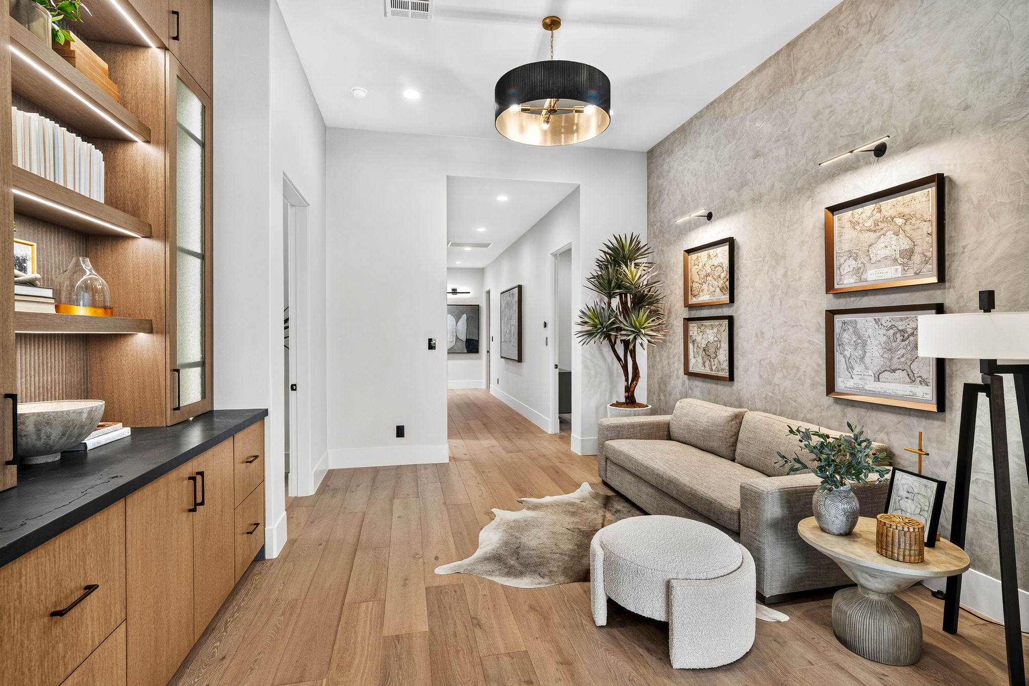 Hallway featuring wood-finish flooring, built-in shelving with integrated lighting, a textured accent wall, and a contemporary ceiling fixture