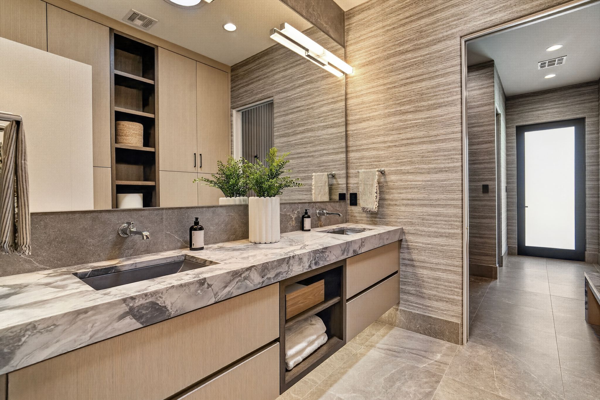 Dual vanity featuring slab countertops, integrated sinks, and wall-mounted faucets