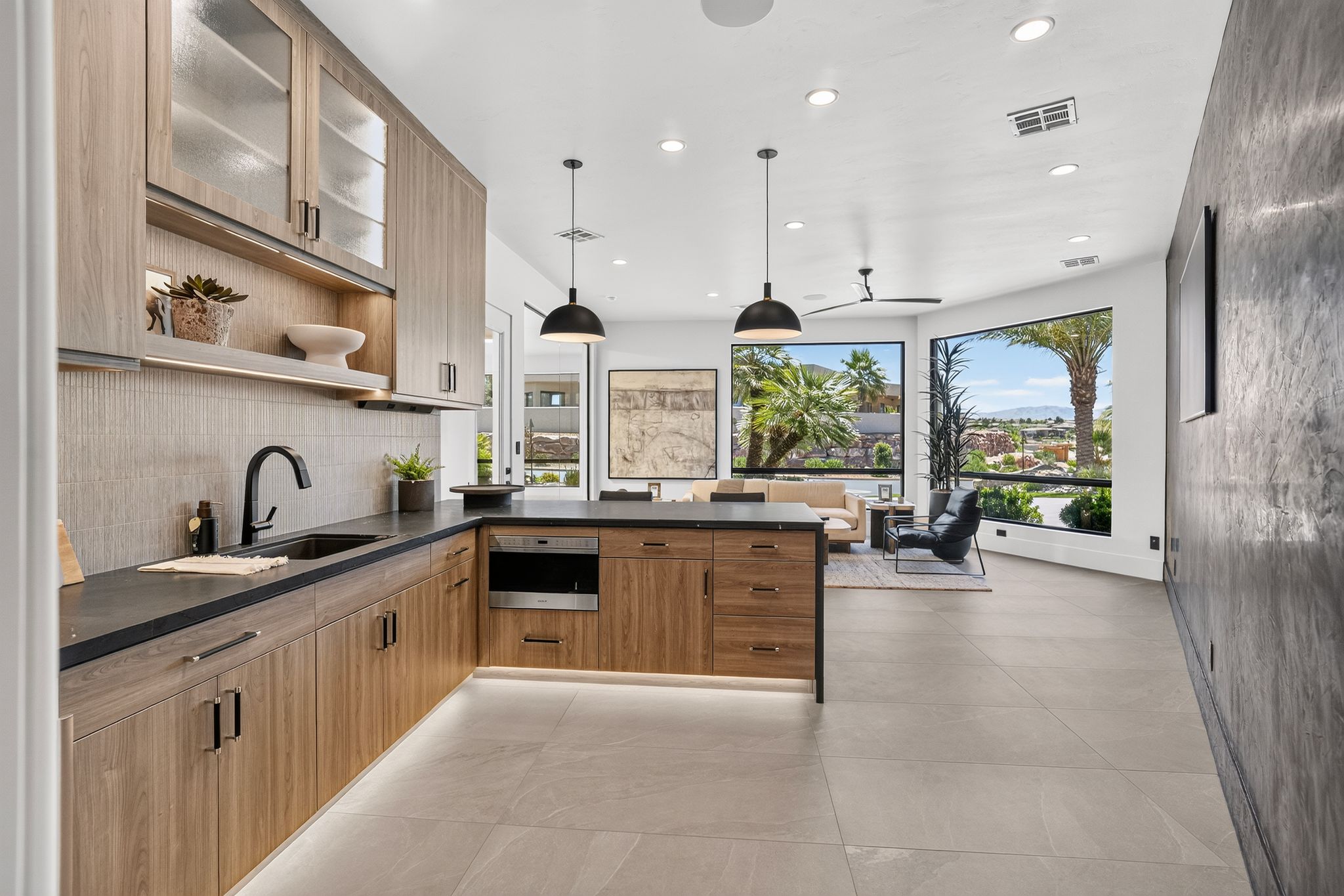 Contemporary kitchen featuring wood-finish cabinetry with frosted glass accents, dark countertops, and a built-in oven