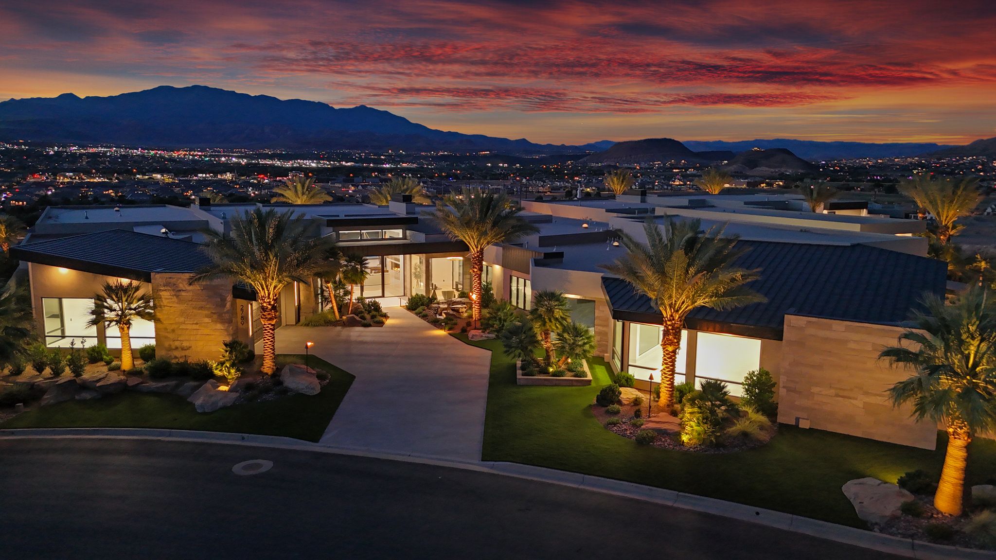 Modern architectural design with a flat roofline, extensive windows, and stone veneer accents