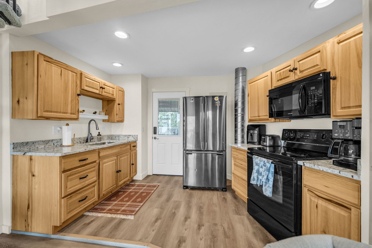Kitchen featuring light wood cabinetry, granite-style countertops, wood-finish flooring, and recessed lighting