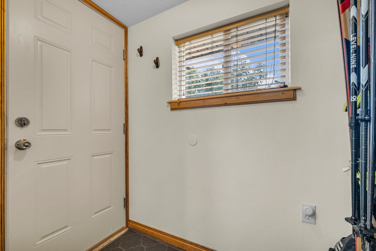 Entryway featuring a paneled door with wood-finish trim, window with blinds, and durable flooring