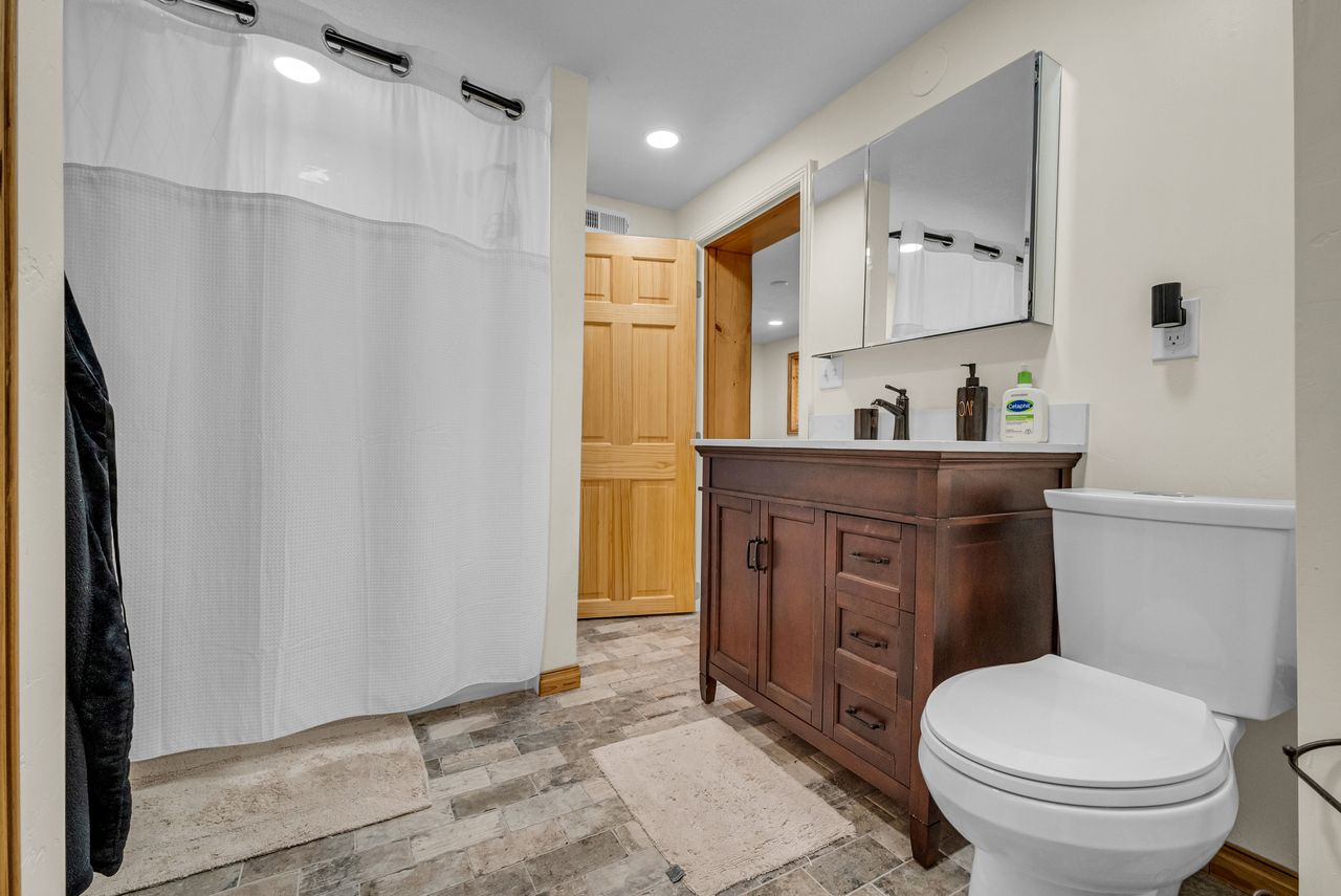 Bathroom featuring a dark wood-finish vanity with a white countertop, coordinating wall-mounted medicine cabinet, and a white toilet