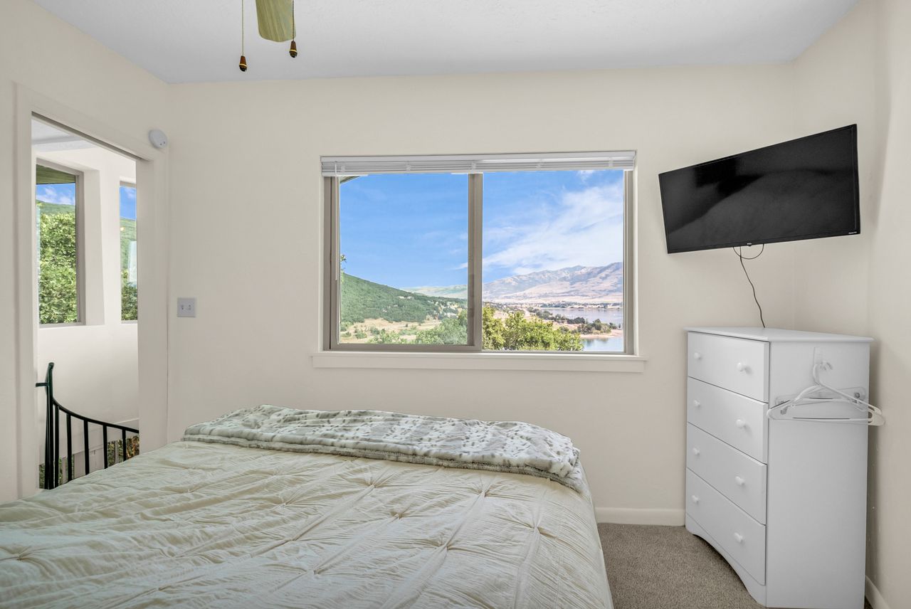 Bedroom featuring a large picture window, carpet flooring, and a ceiling fan